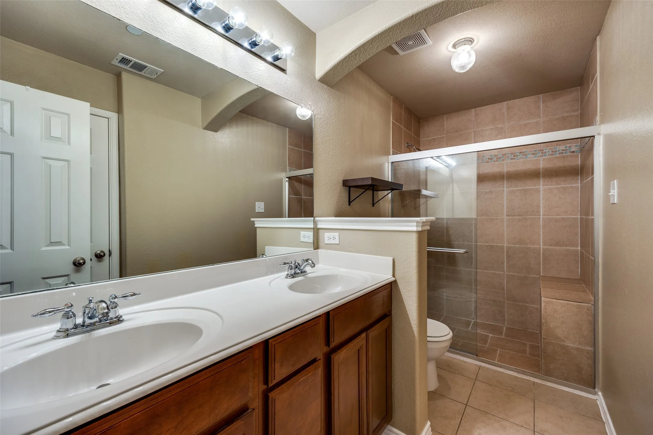 Dual vanity with integrated sinks, wood-finish cabinetry, and chrome fixtures