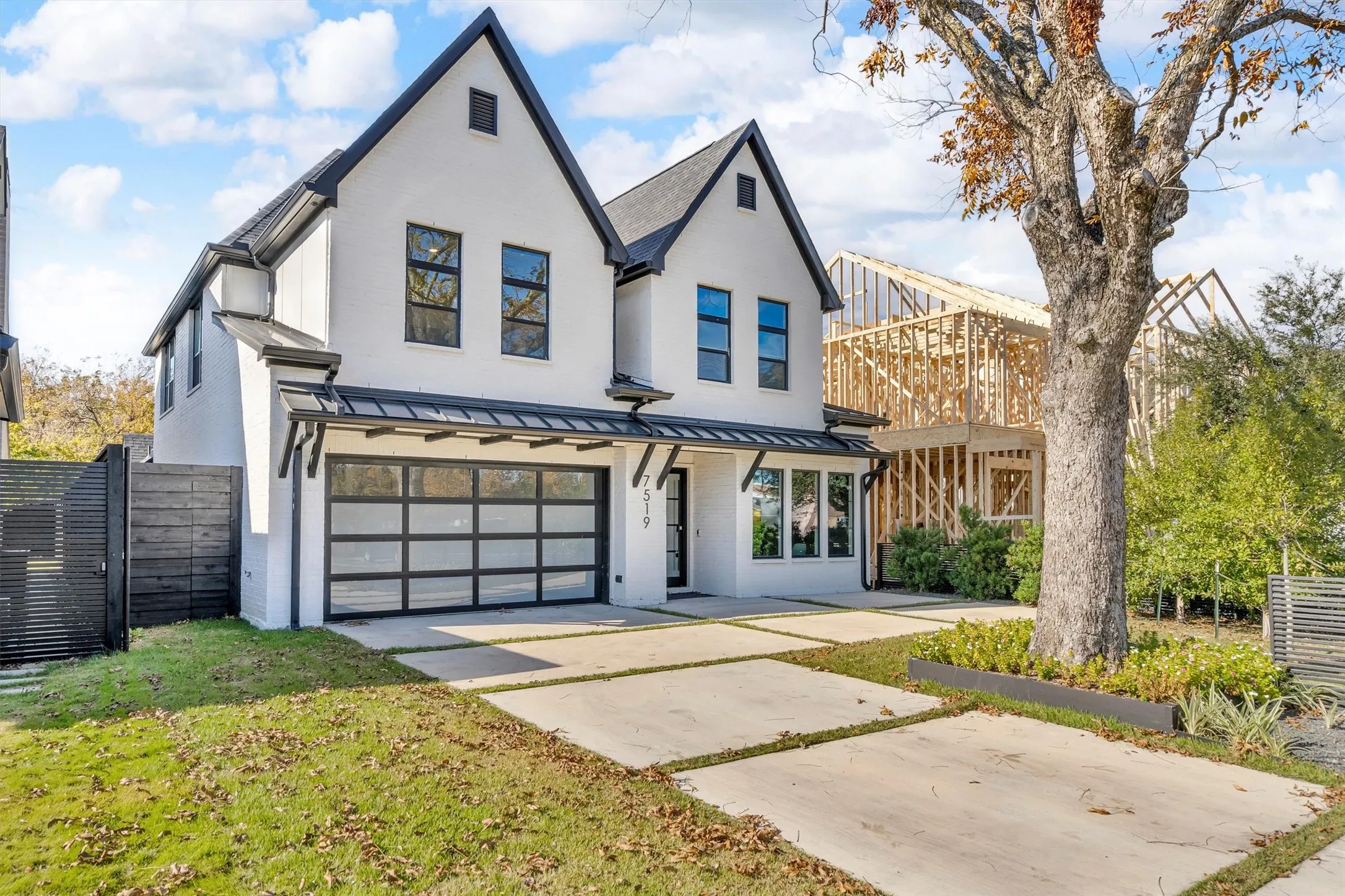 Modern exterior with a white stucco finish, black trim accents, a full-view garage door, and a concrete paver driveway