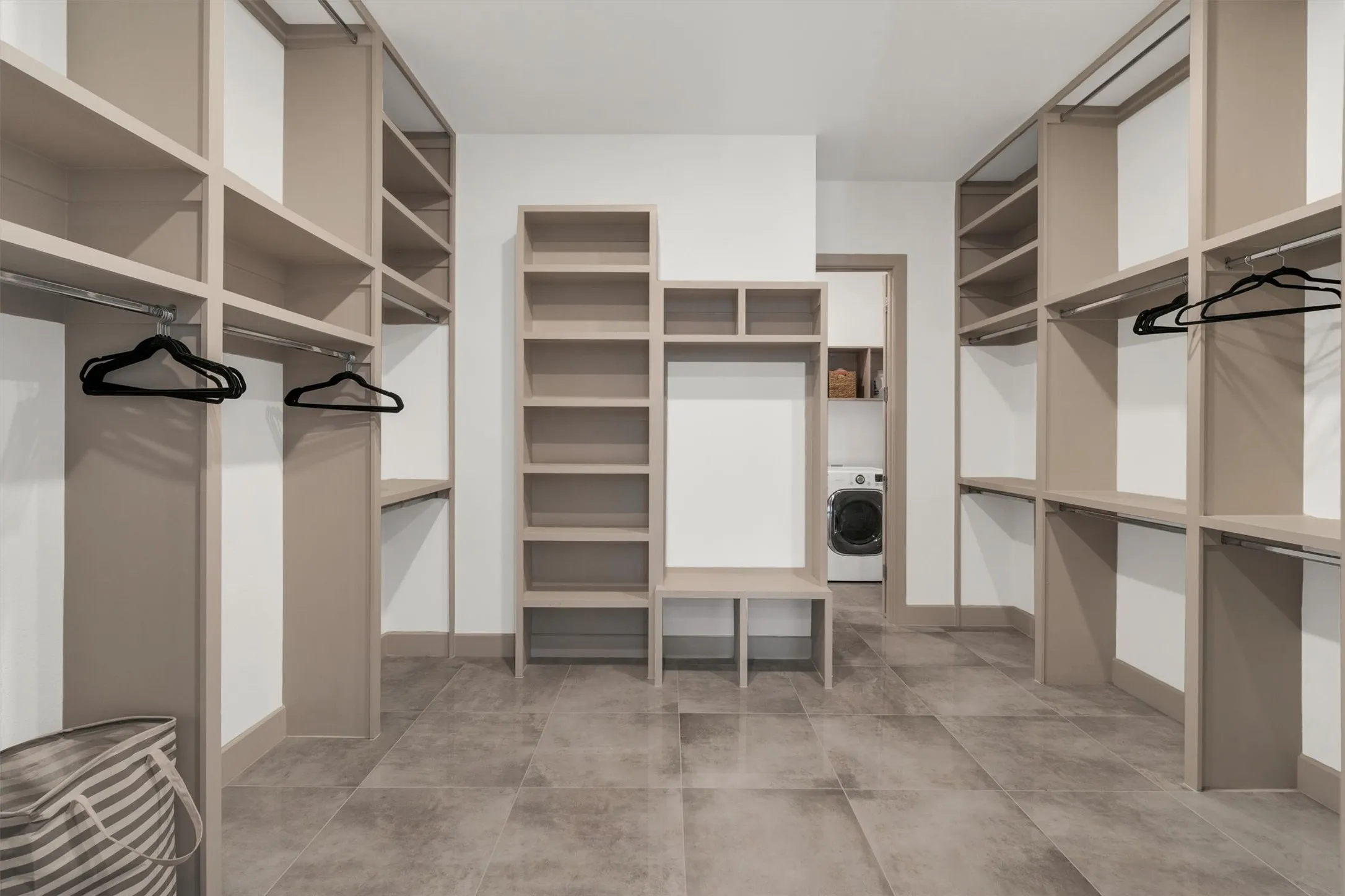 Built-in closet system with shelving and hanging rods, center storage unit, and tile flooring
