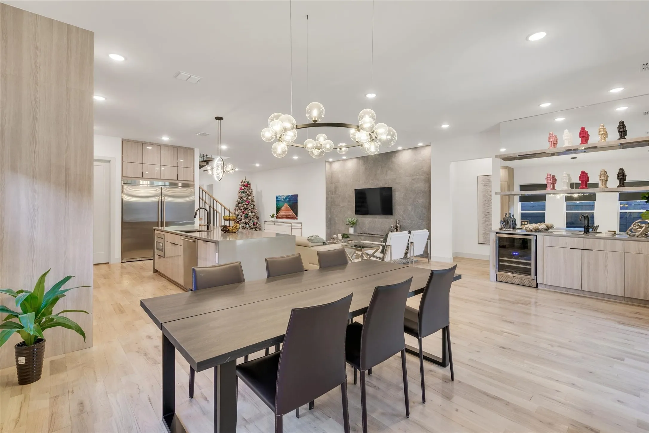 Open-concept living space with light wood-finish flooring, recessed lighting, and a contemporary bubble chandelier