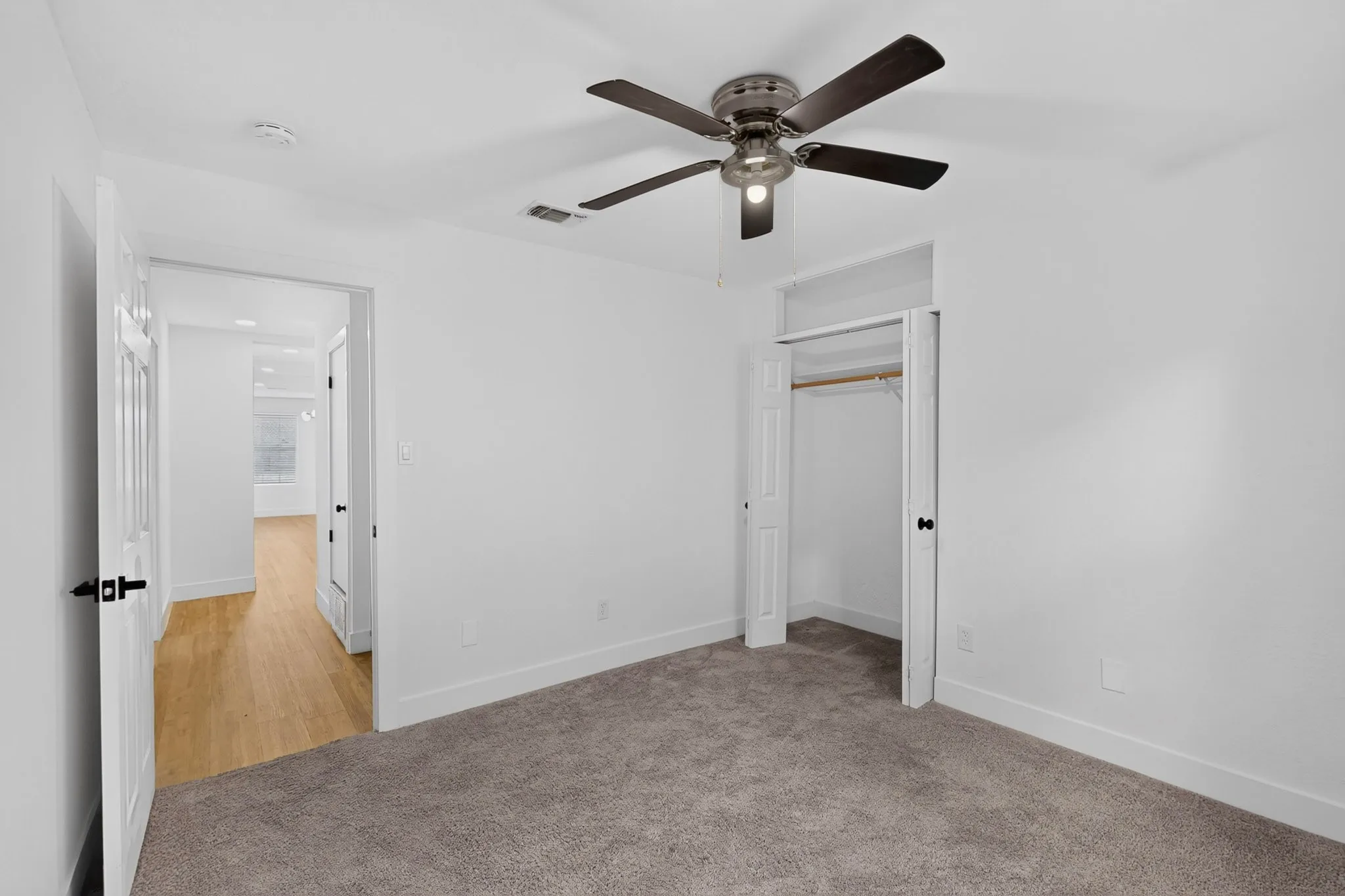Plush carpet flooring, ceiling fan with integrated lighting, white interior doors, and a built-in closet with hanging rod
