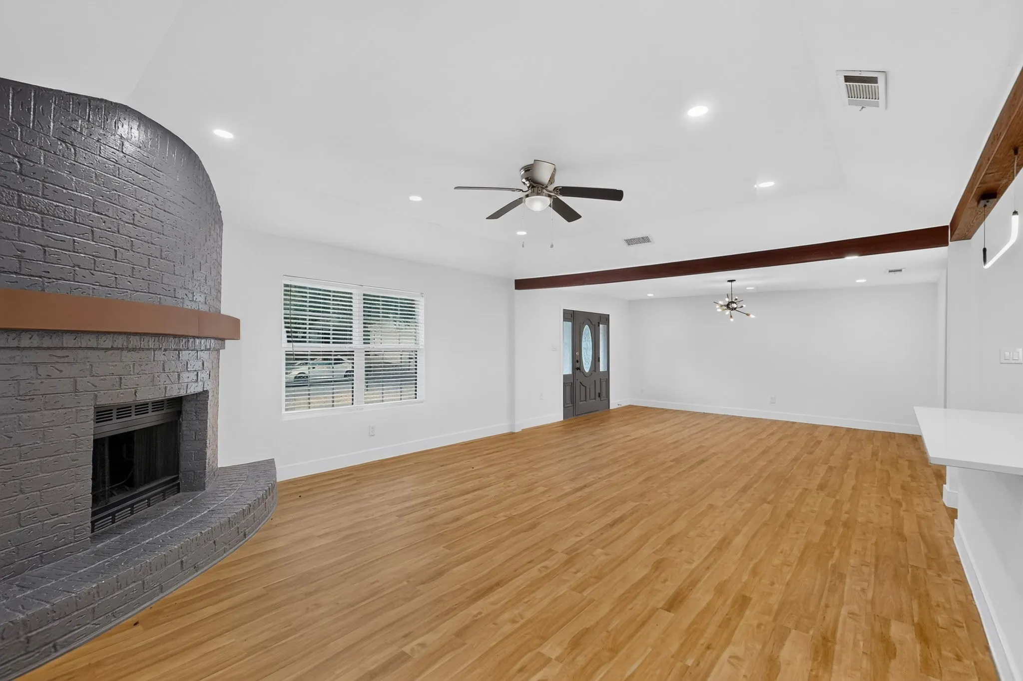 Spacious open-concept living area featuring hardwood flooring, recessed lighting, and ceiling fan
