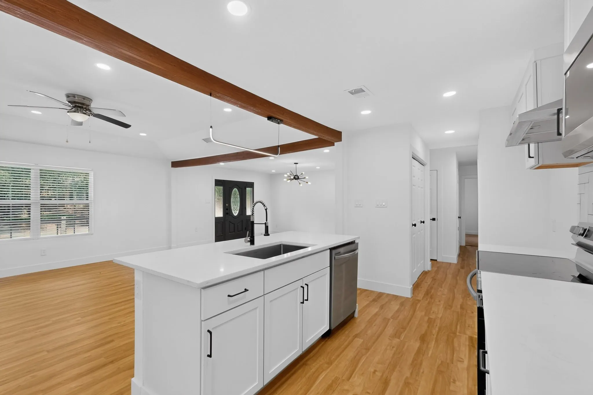 Kitchen island with white countertops, integrated sink, and stainless steel dishwasher