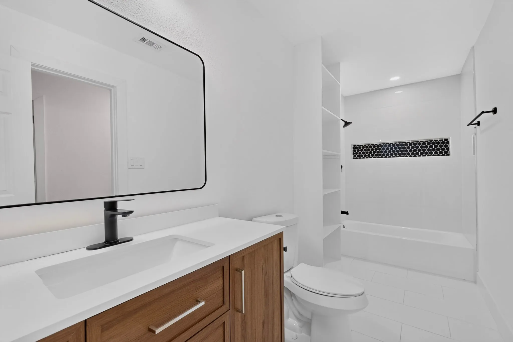 Modern bathroom featuring a wood-finish vanity with dual-handle matte black faucet, white quartz countertop, and rectangular vessel sink