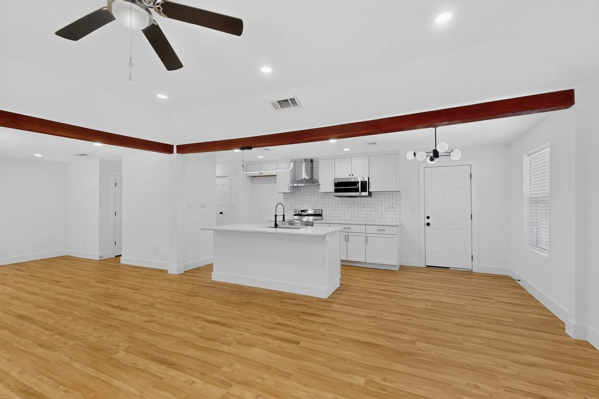 Open-concept living and kitchen area featuring wood-finish flooring throughout, recessed ceiling lighting, and a ceiling fan