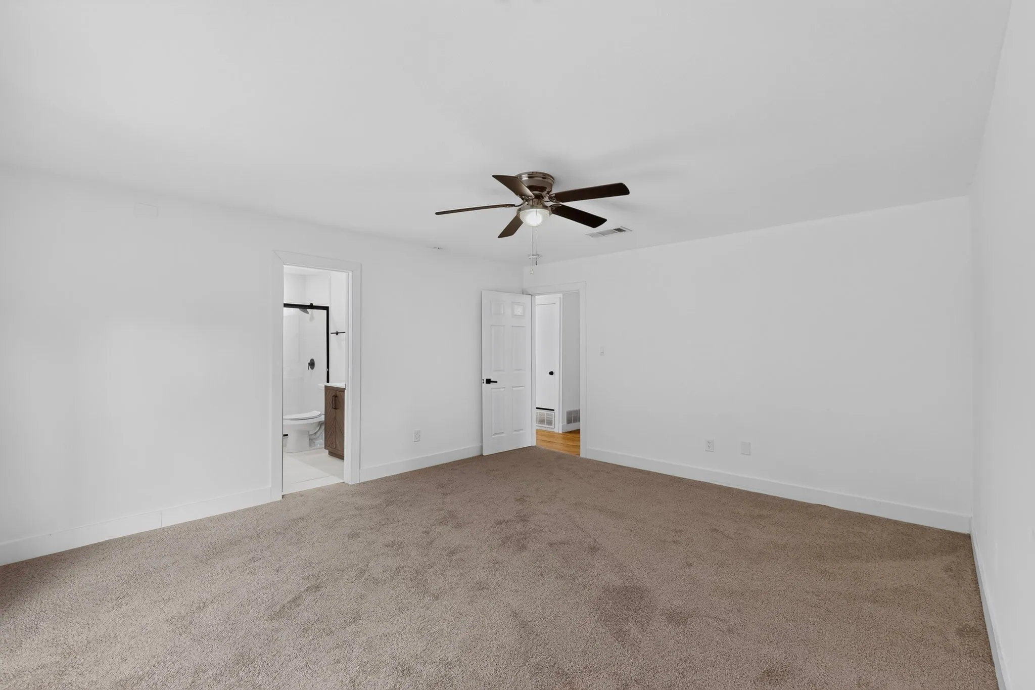 Spacious room featuring neutral carpet flooring, white walls, and a ceiling fan with integrated lighting