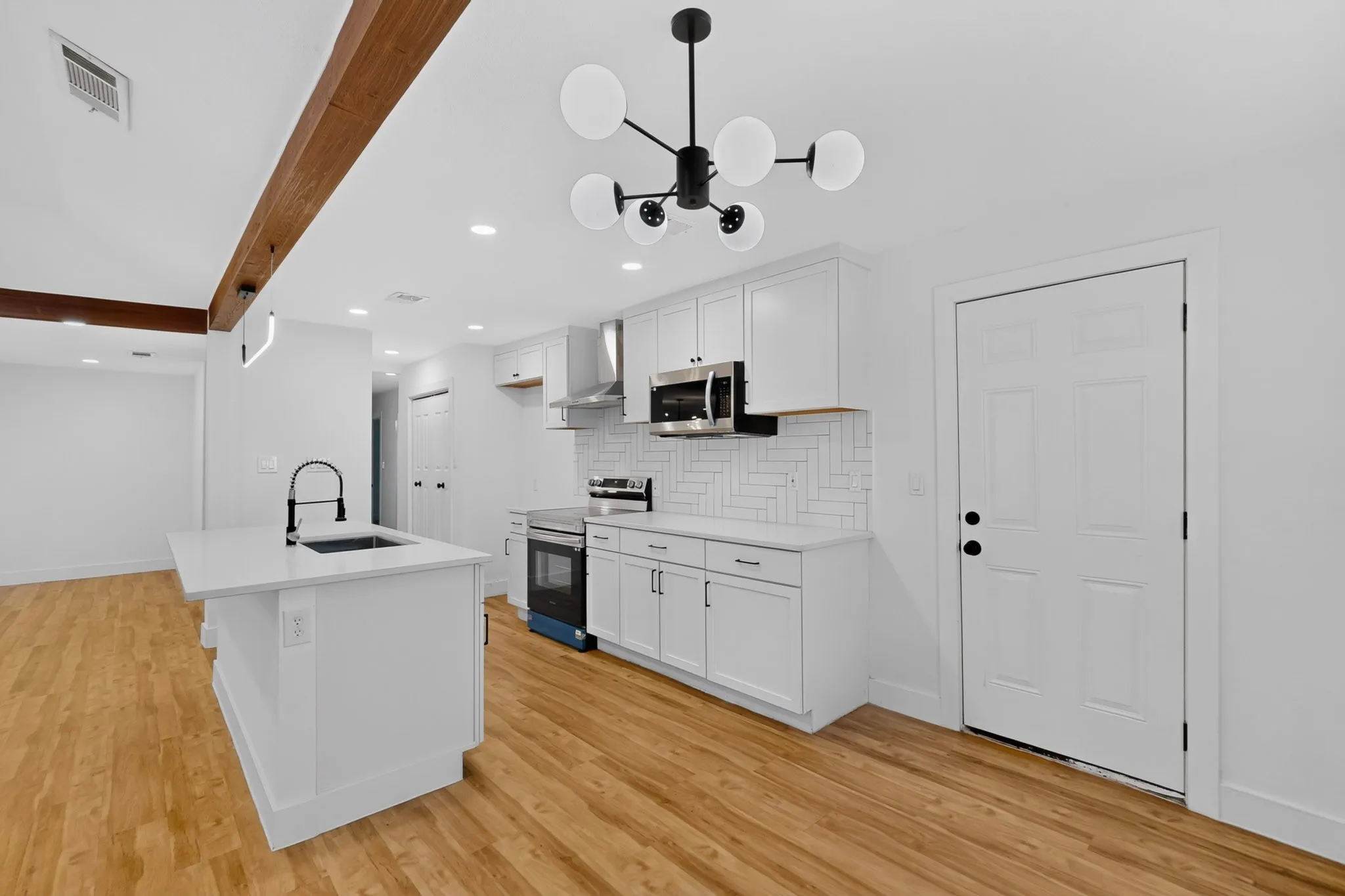 Modern kitchen featuring white cabinetry, stainless steel appliances, subway tile backsplash, and a waterfall-edge island with seating
