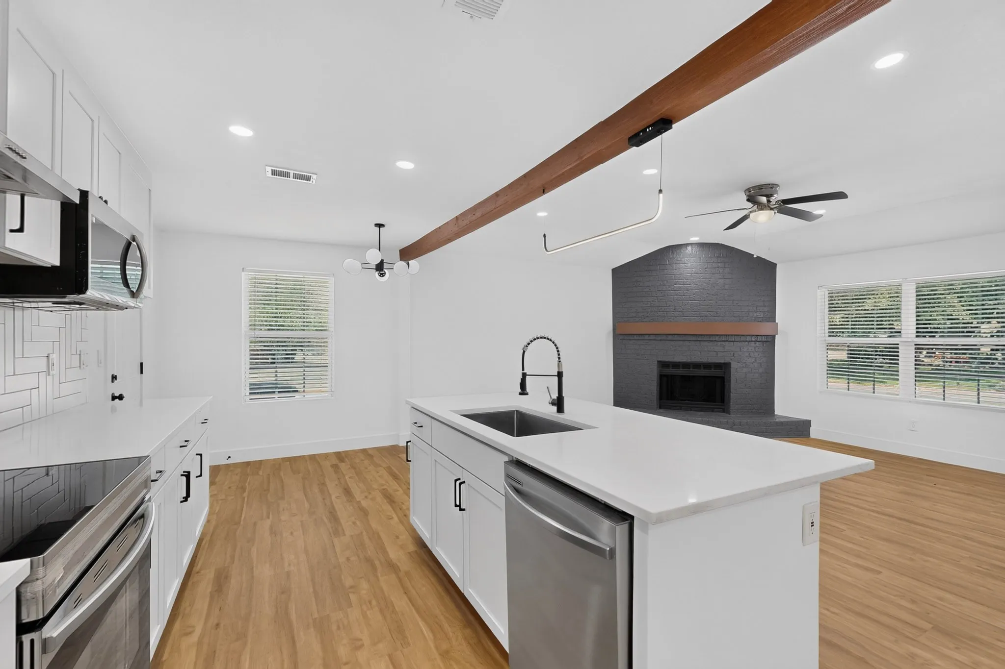 Modern kitchen featuring white cabinetry, stainless steel appliances, and a white quartz island countertop with undermount sink