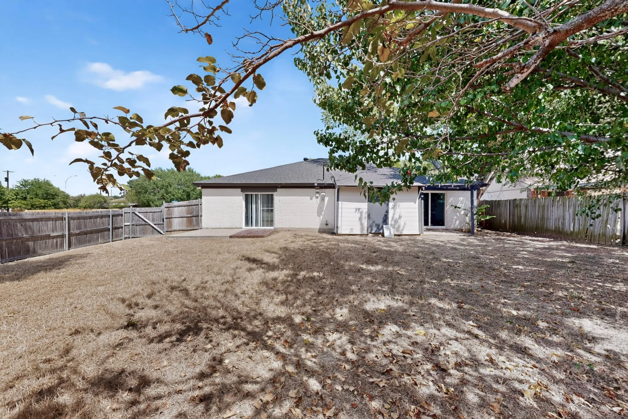 Expansive fenced backyard featuring a patio area and a single-story exterior with a sliding glass door