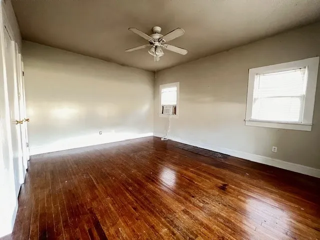 Empty room featuring dark wood-type flooring and ceiling fan