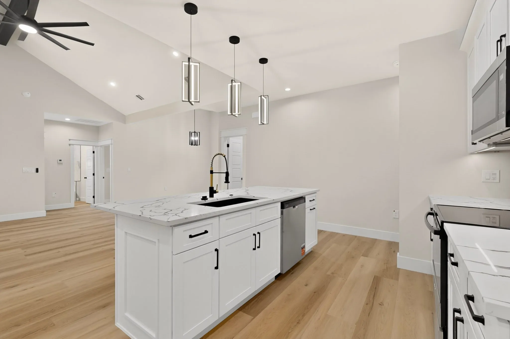 Kitchen featuring a central island with a black sink and faucet, white cabinetry, and light-toned wood-finish flooring