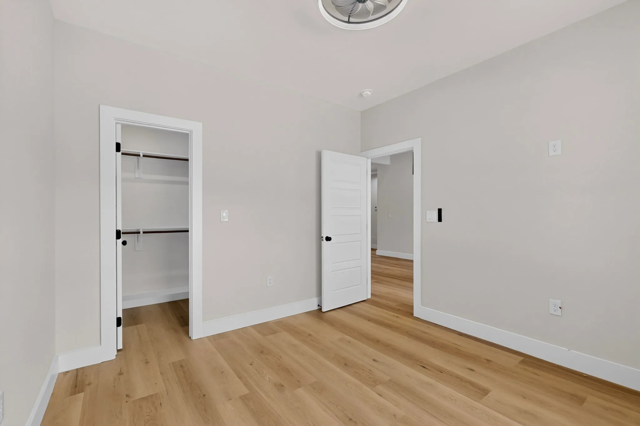 Wood-finish flooring, white paneled doors, ceiling light fixture, and closet with shelving