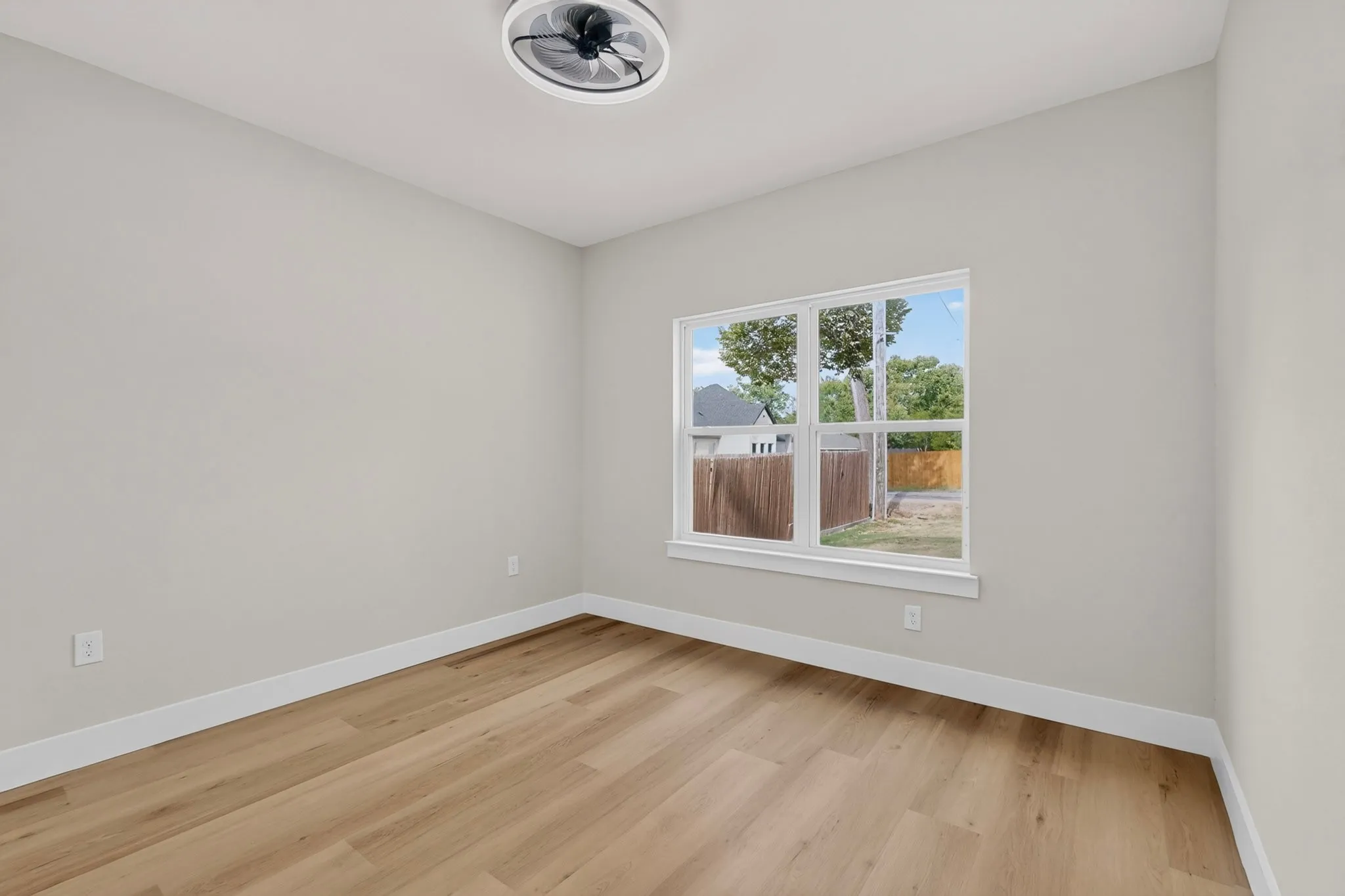 Recessed ceiling light with fan, wood-finish flooring, white walls, and a large window