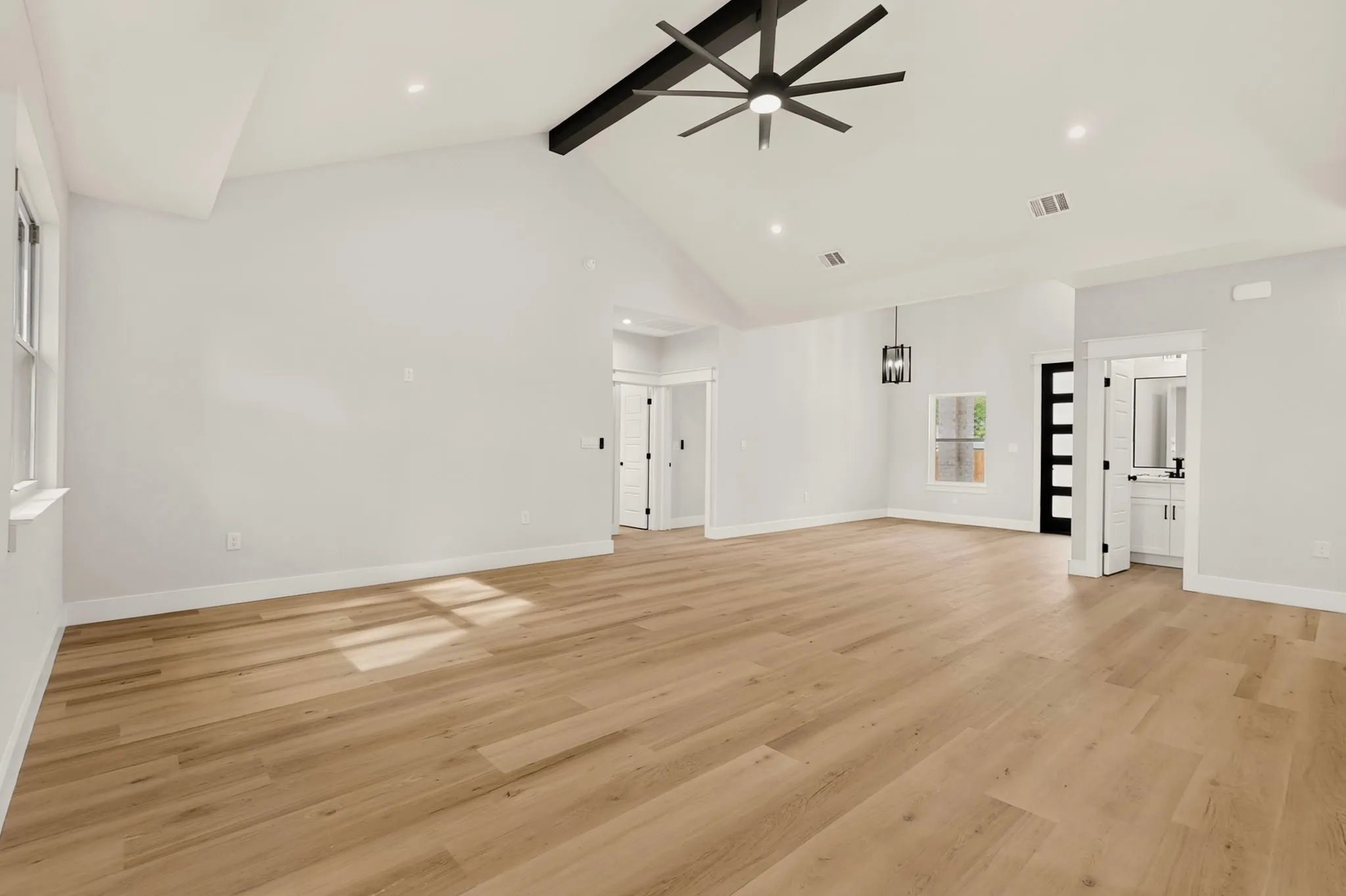 Vaulted ceiling with an exposed beam, wood-finish flooring, recessed lighting, modern ceiling fan, and a contemporary pendant light fixture