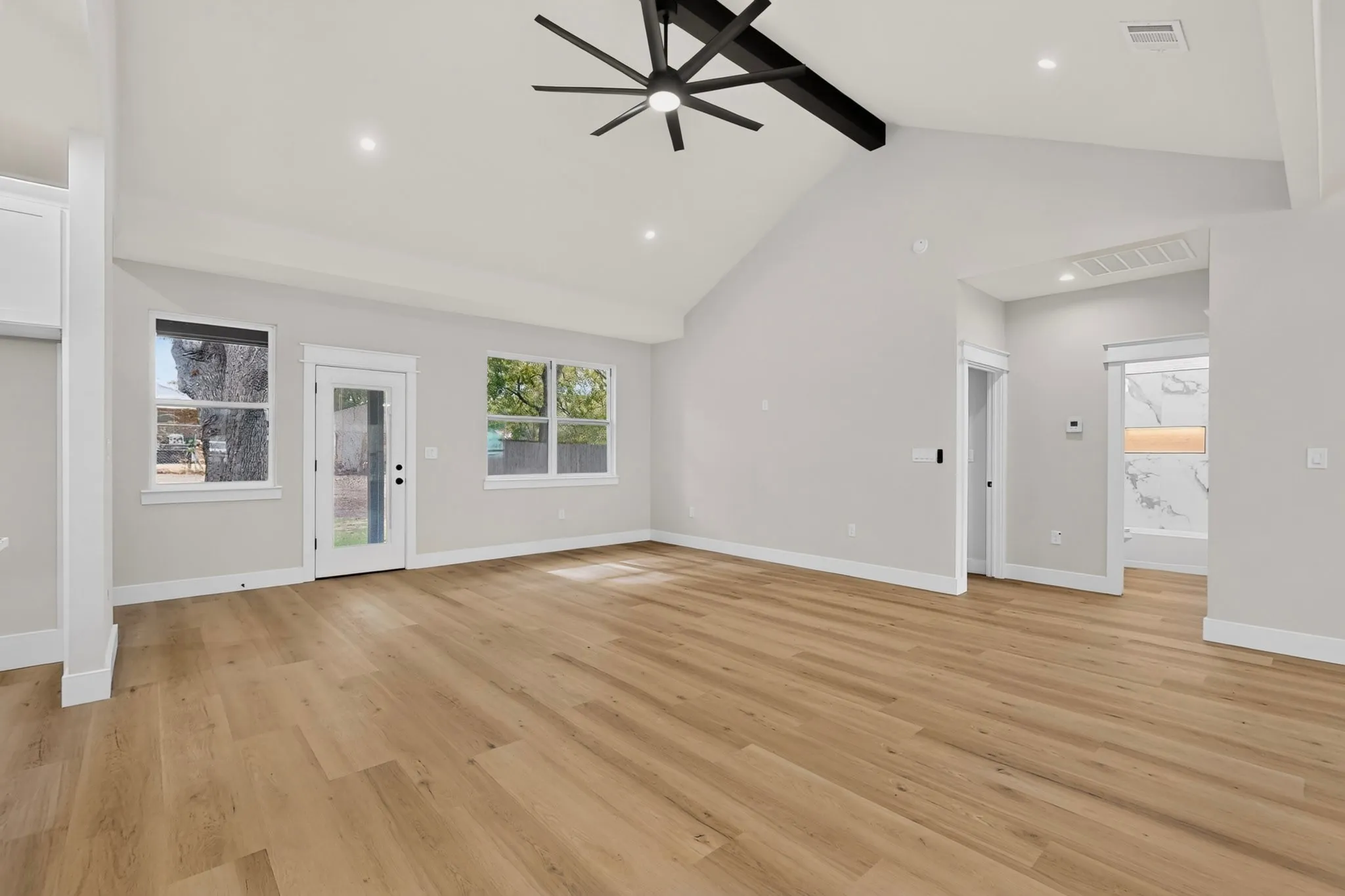 Vaulted ceilings with exposed beam, wood-finish flooring, recessed lighting, and a modern ceiling fan