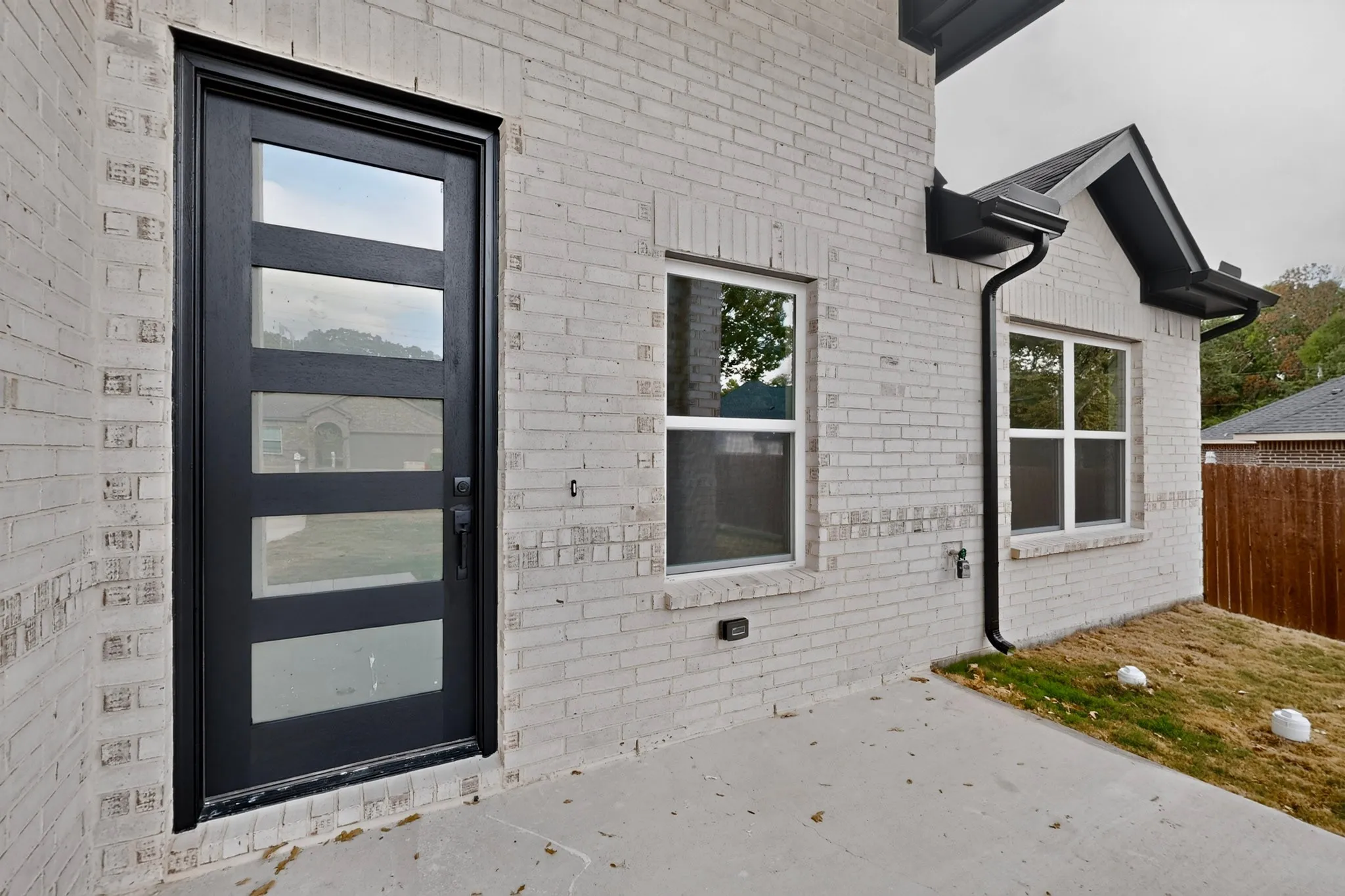 Brick exterior with a contemporary black entry door featuring four clear glass panels