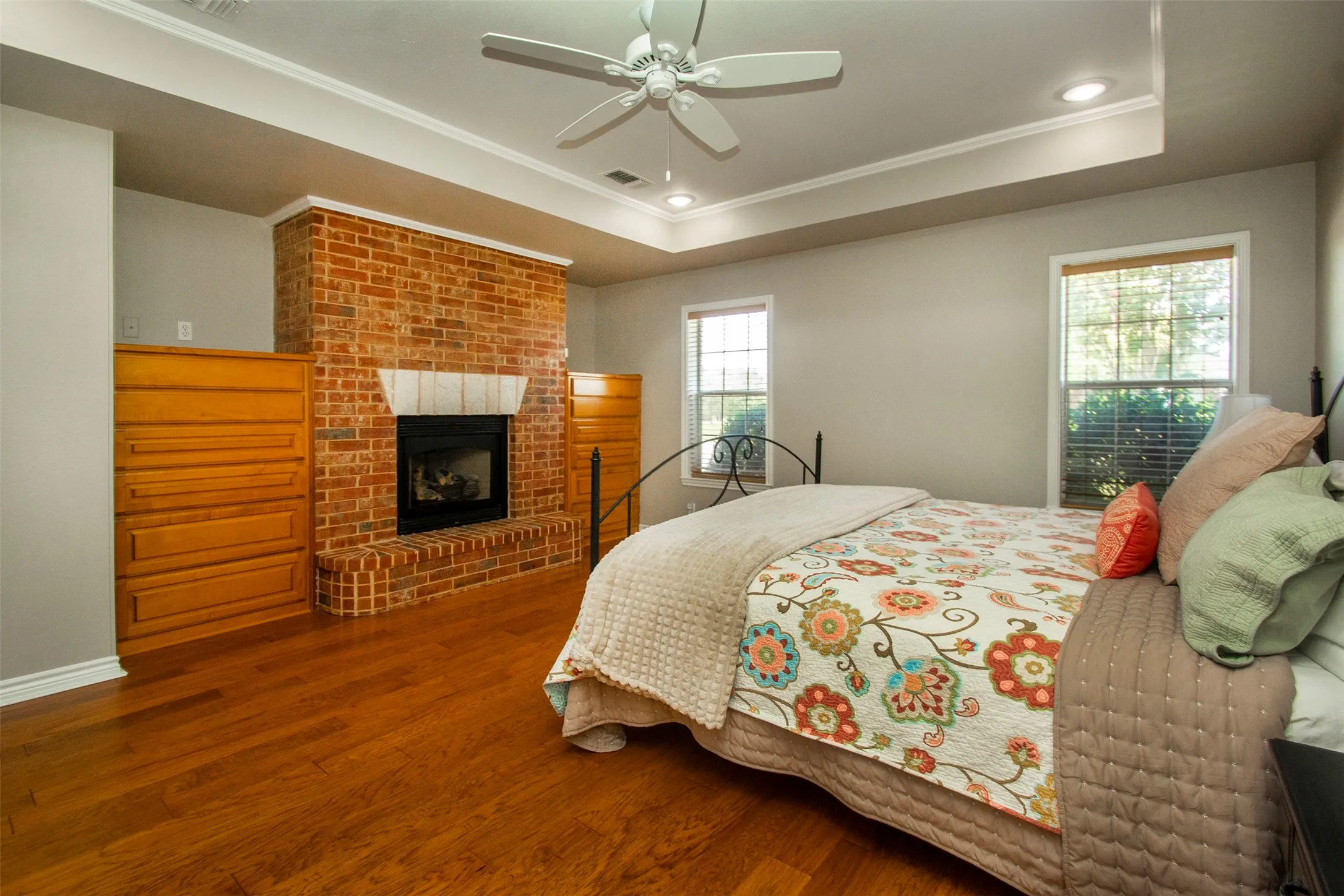 Spacious primary bedroom with built in gas fireplace and custom built dressers