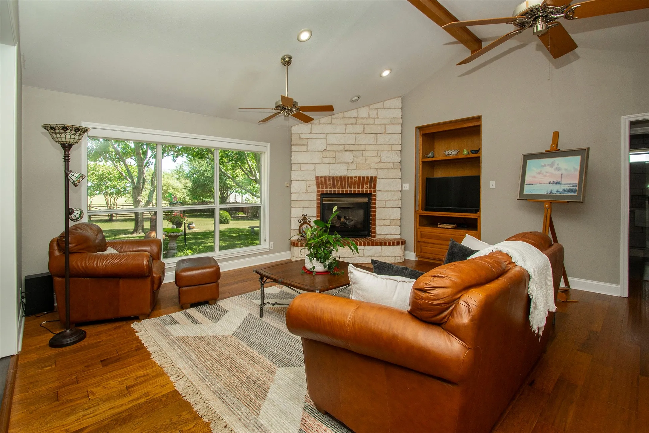 Spacious living room with built in entertainment cabinet and brick/rock gas fireplace