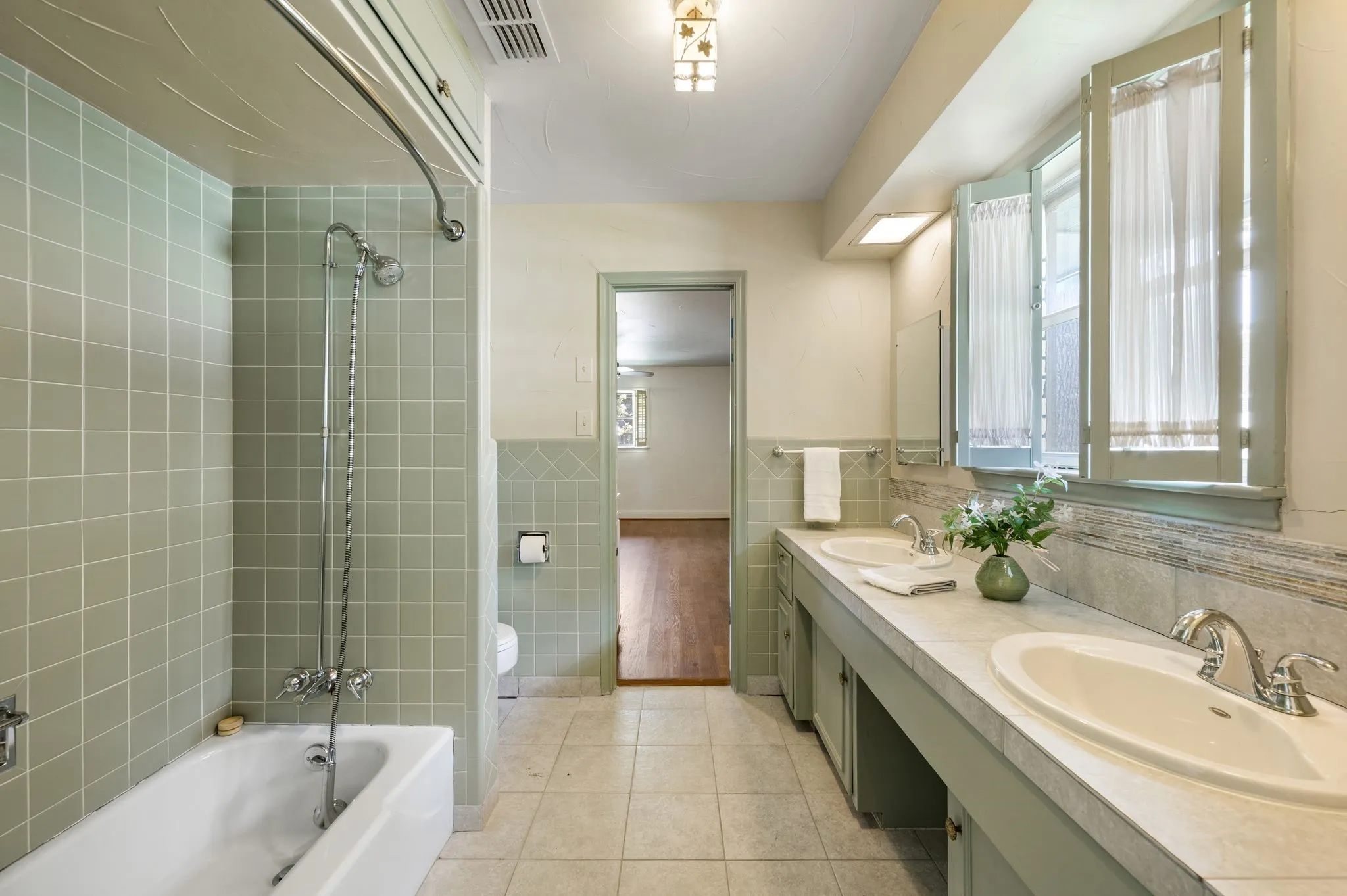 Charming jack and jill bath retains original tile and pretty wood shutters
