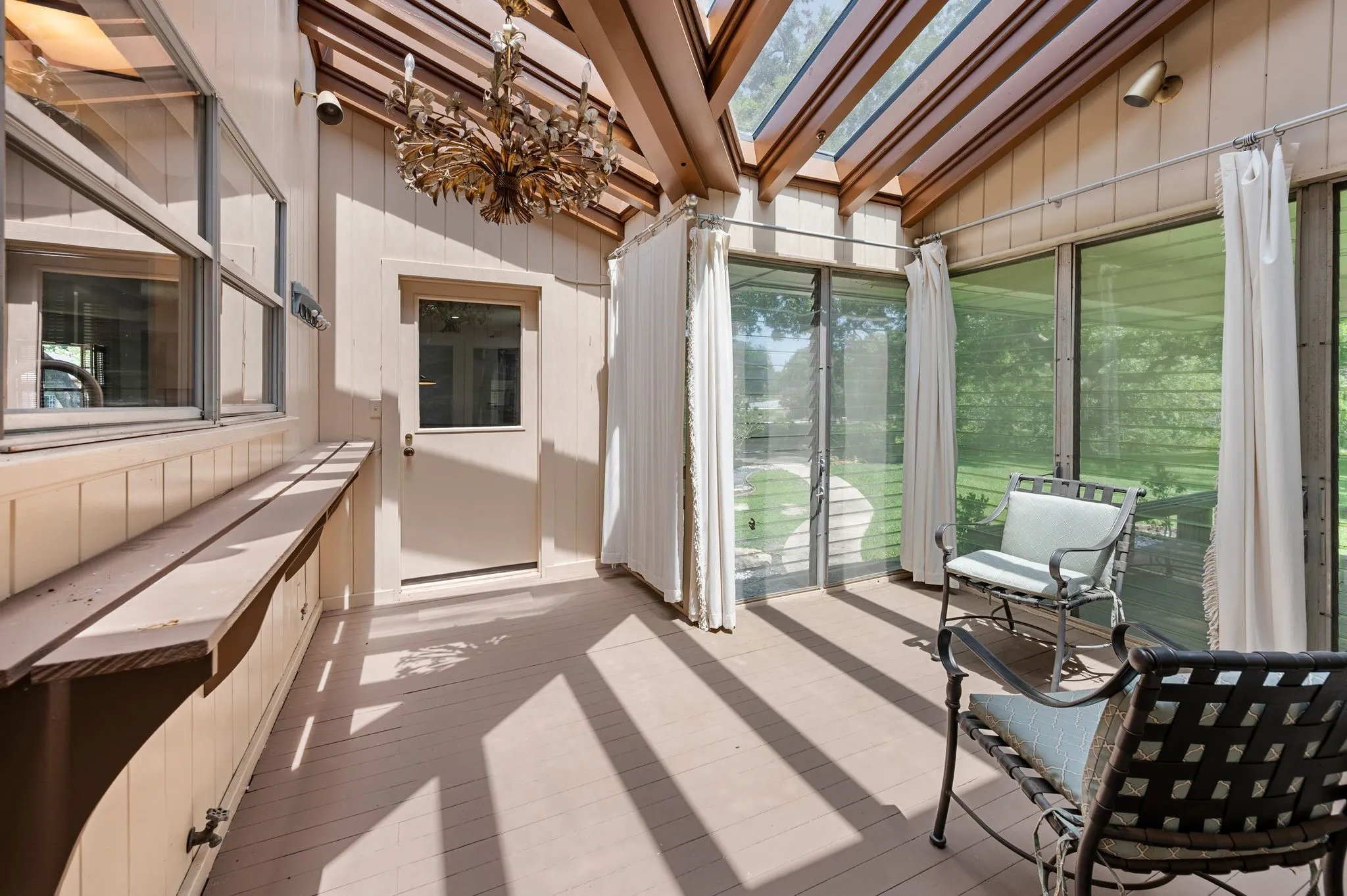 Fantastic chandelier in the charming sun room, complete with vintage glass louvered windows.