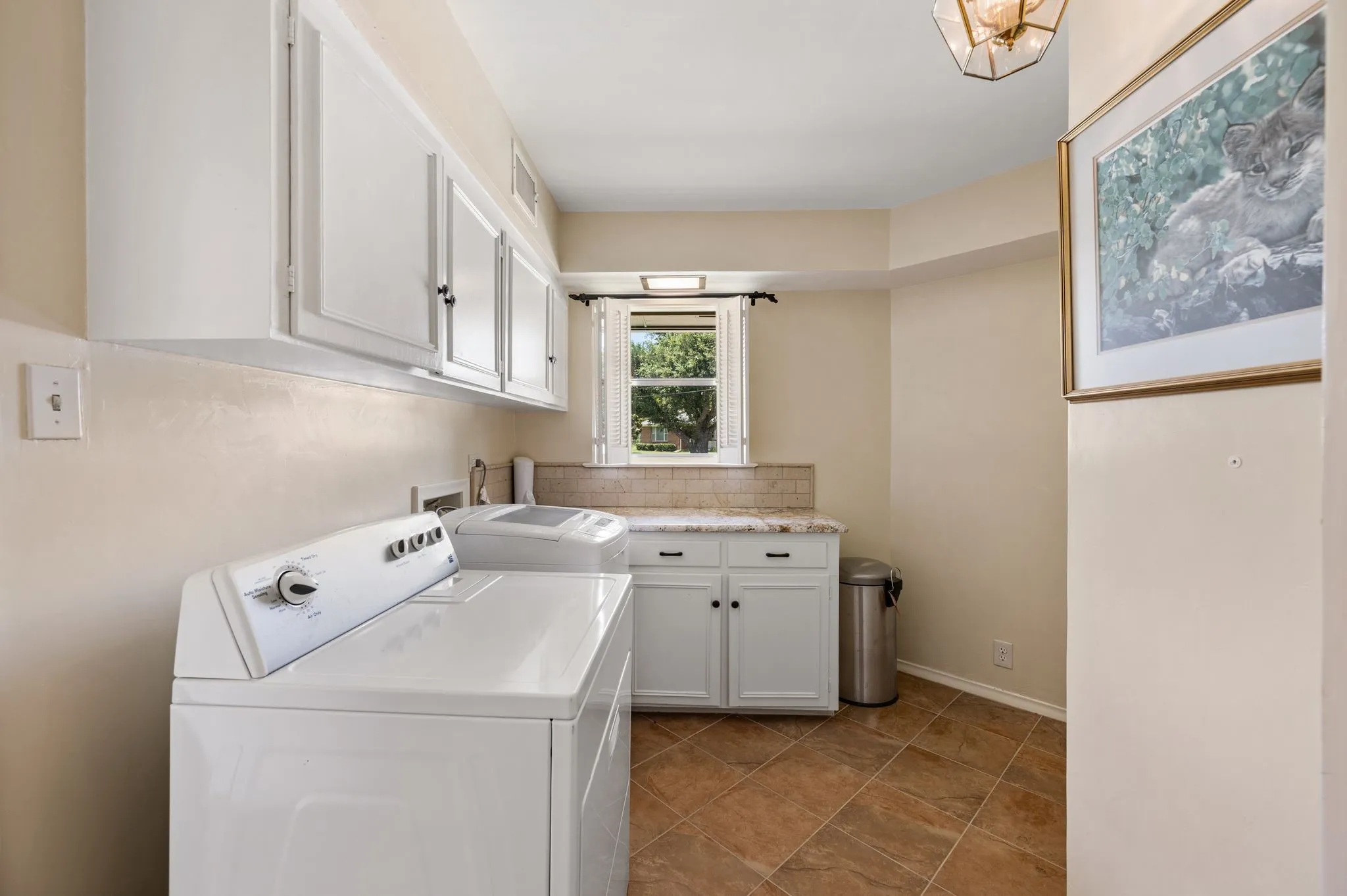 Oversized laundry has upper and lower cabinets and plenty of room for storage