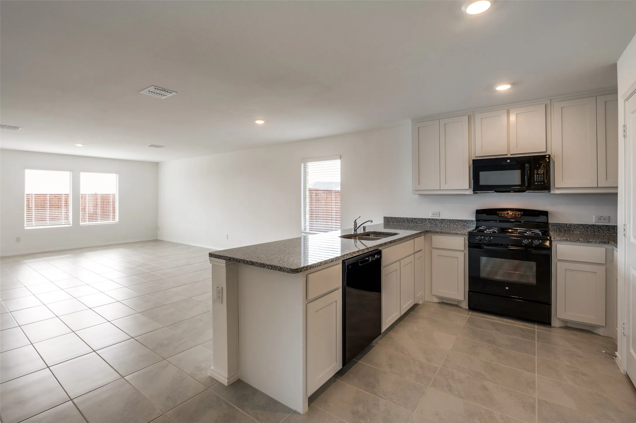 Kitchen island with an undermount sink, granite countertops, and white shaker-style cabinetry