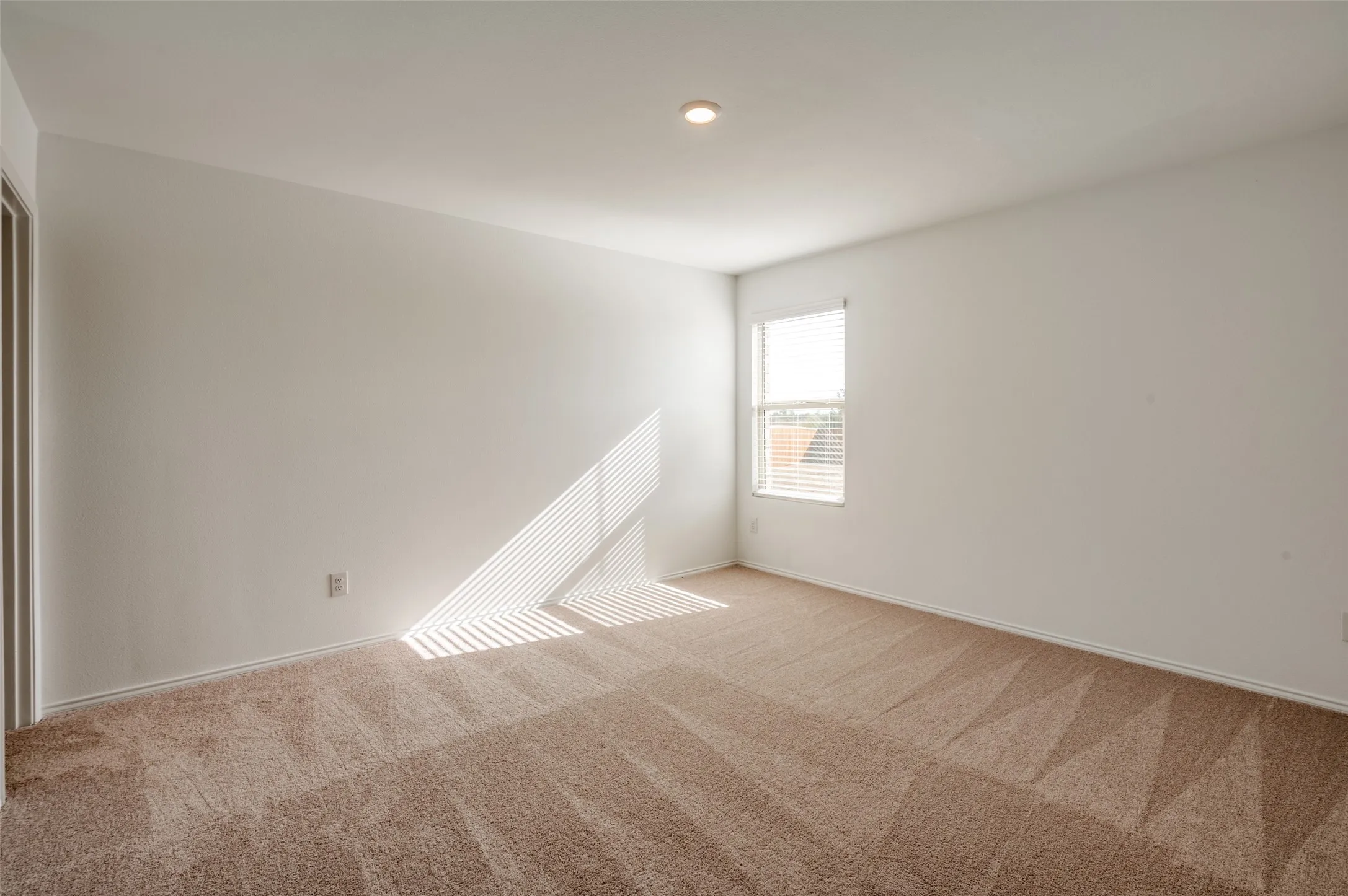 Recessed lighting, neutral wall tones, window with horizontal blinds, and patterned carpet flooring