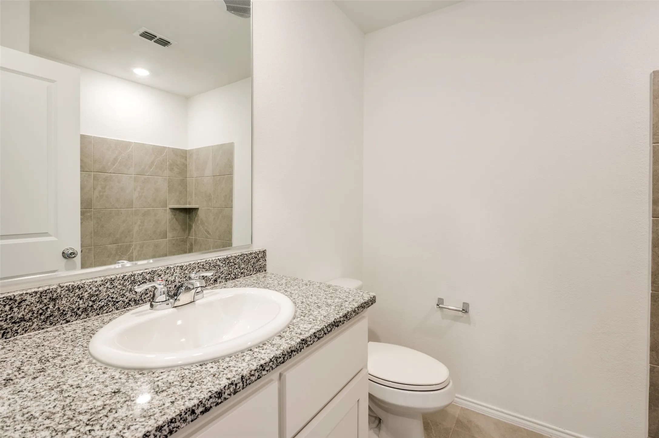 Vanity with speckled countertop, undermount sink, and chrome faucet