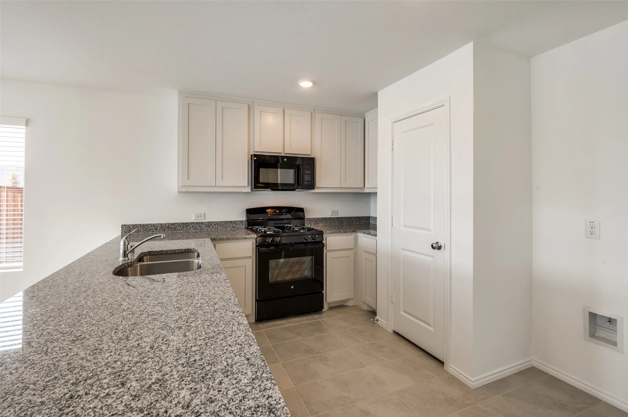 Kitchen featuring white cabinetry, granite countertops, a stainless steel double basin sink, a black gas range, and recessed lighting