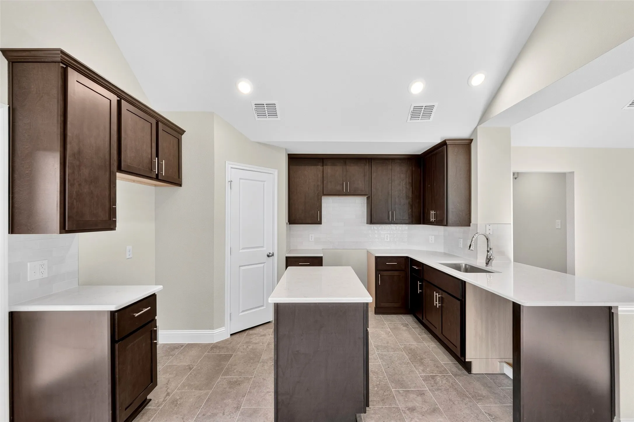 Kitchen featuring dark wood cabinetry, white countertops, tile flooring, recessed lighting, and a kitchen island
