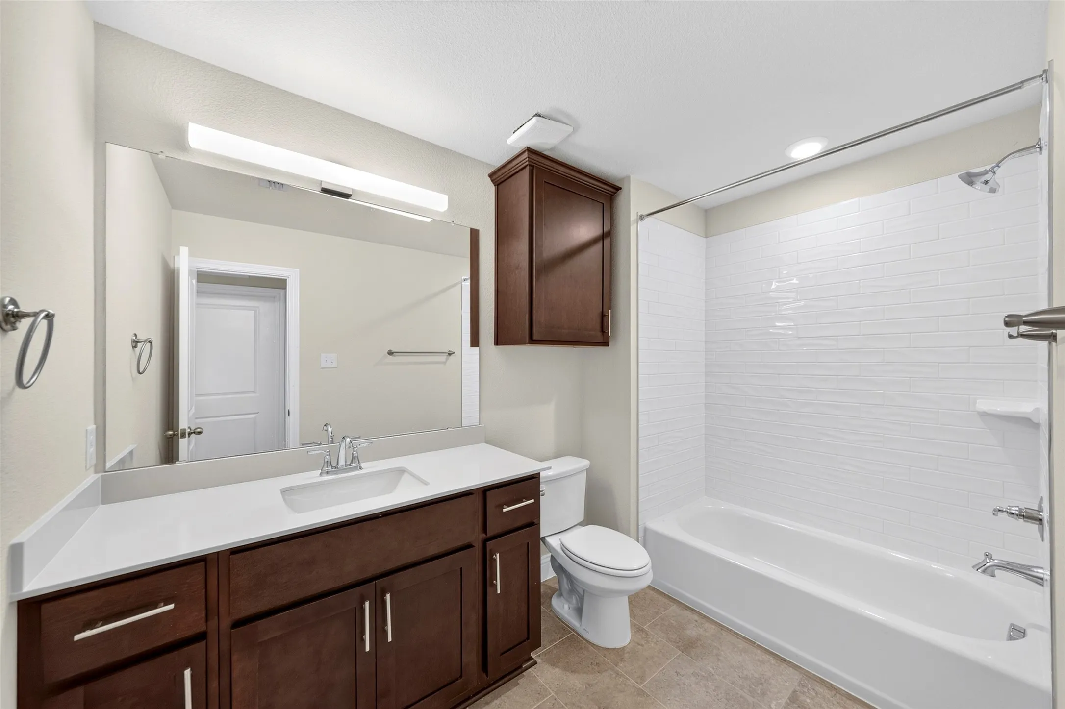 Spacious vanity with white countertop, undermount sink, and wood-finish cabinetry