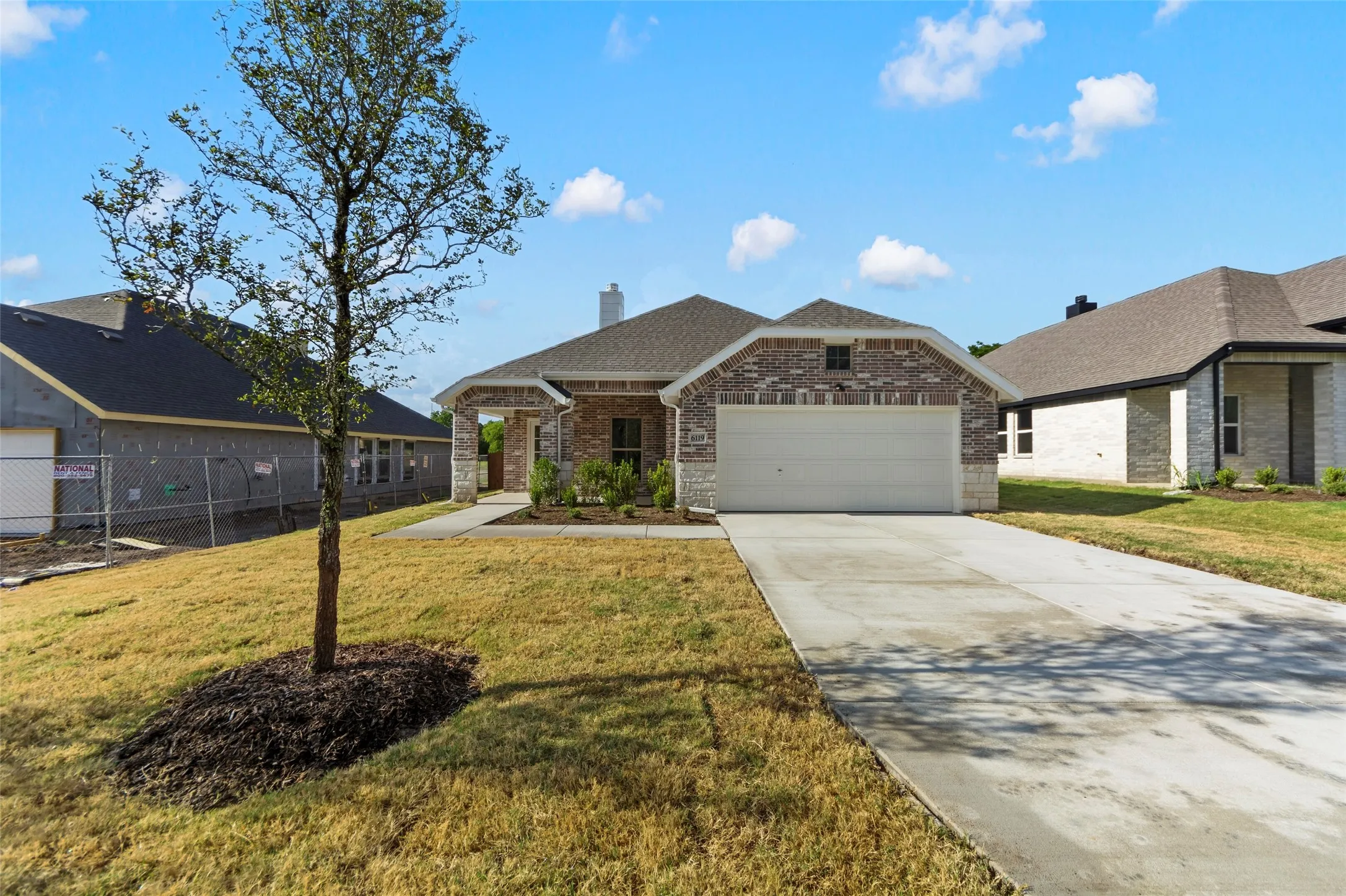 Brick and stone facade with an attached two-car garage, concrete driveway, and a well-maintained front lawn