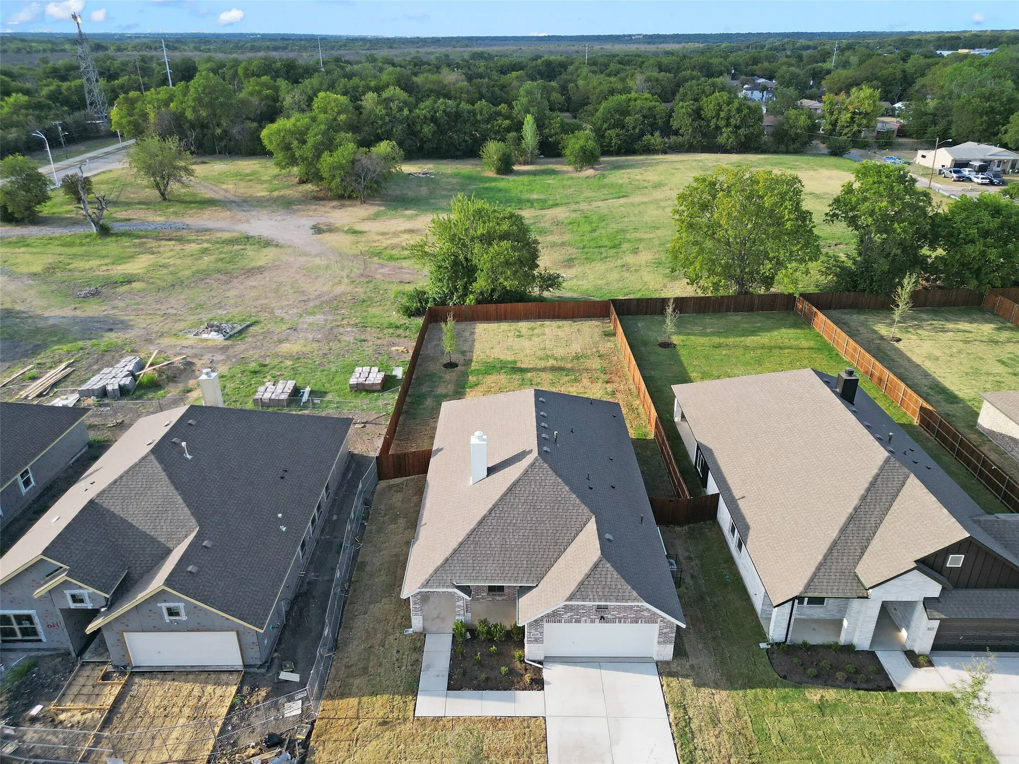 New construction home featuring a light-colored brick and stone exterior, a dark shingle roof, and an attached two-car garage