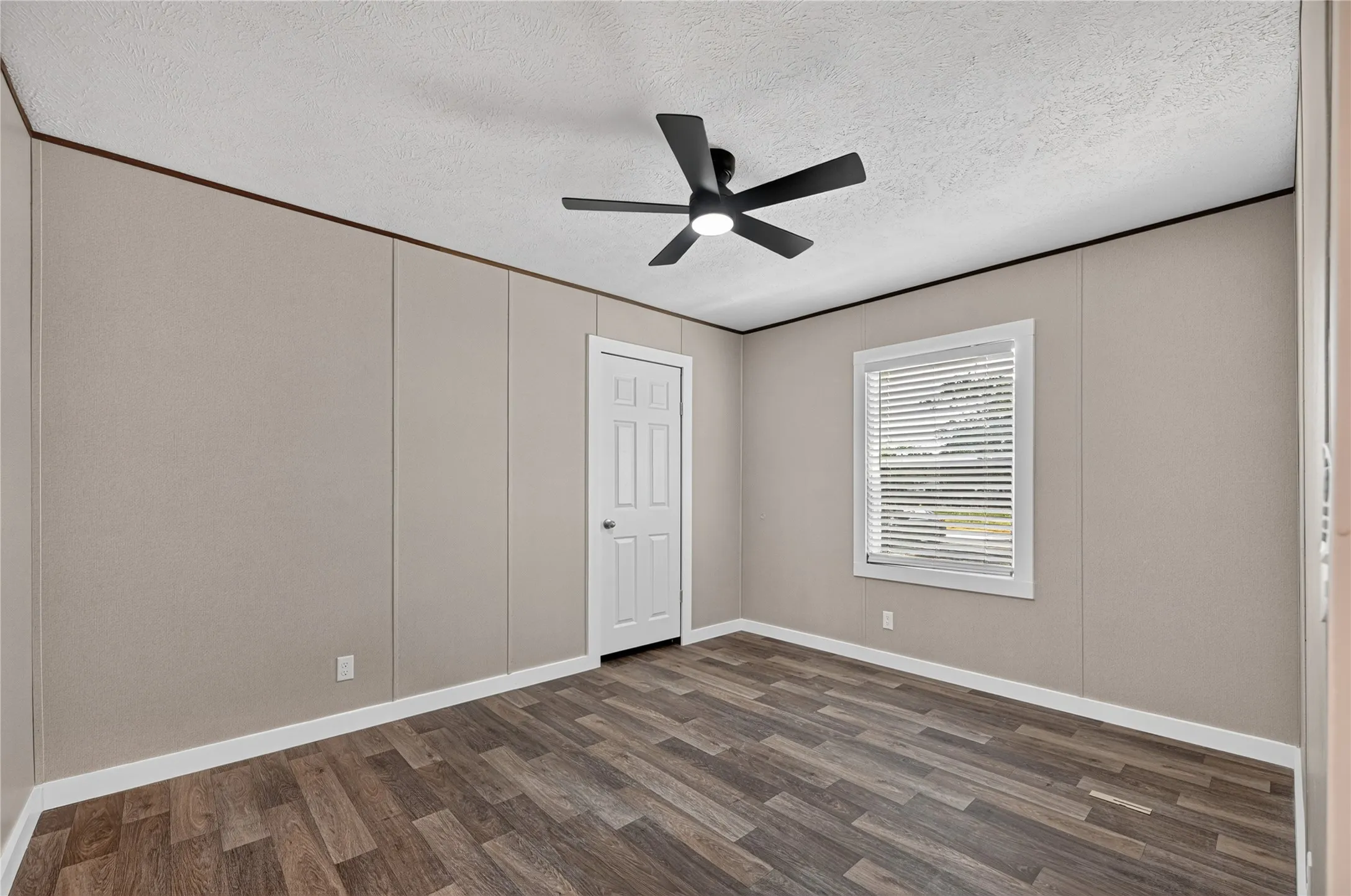 Wood-finish flooring, ceiling fan with integrated lighting, two panel doors, and neutral wall tones