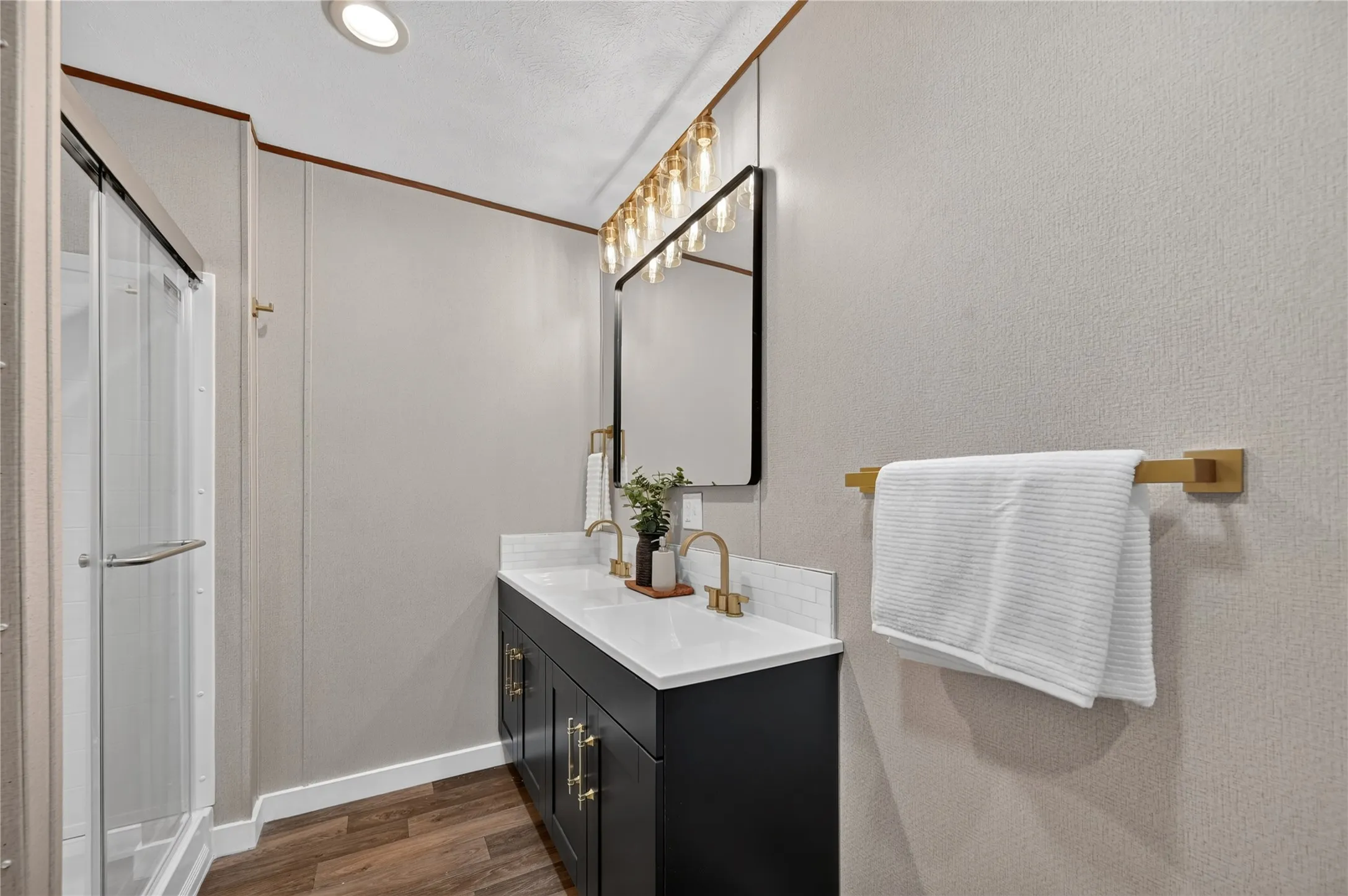 Dual vanity with white countertop, dark cabinetry, and gold-finish hardware