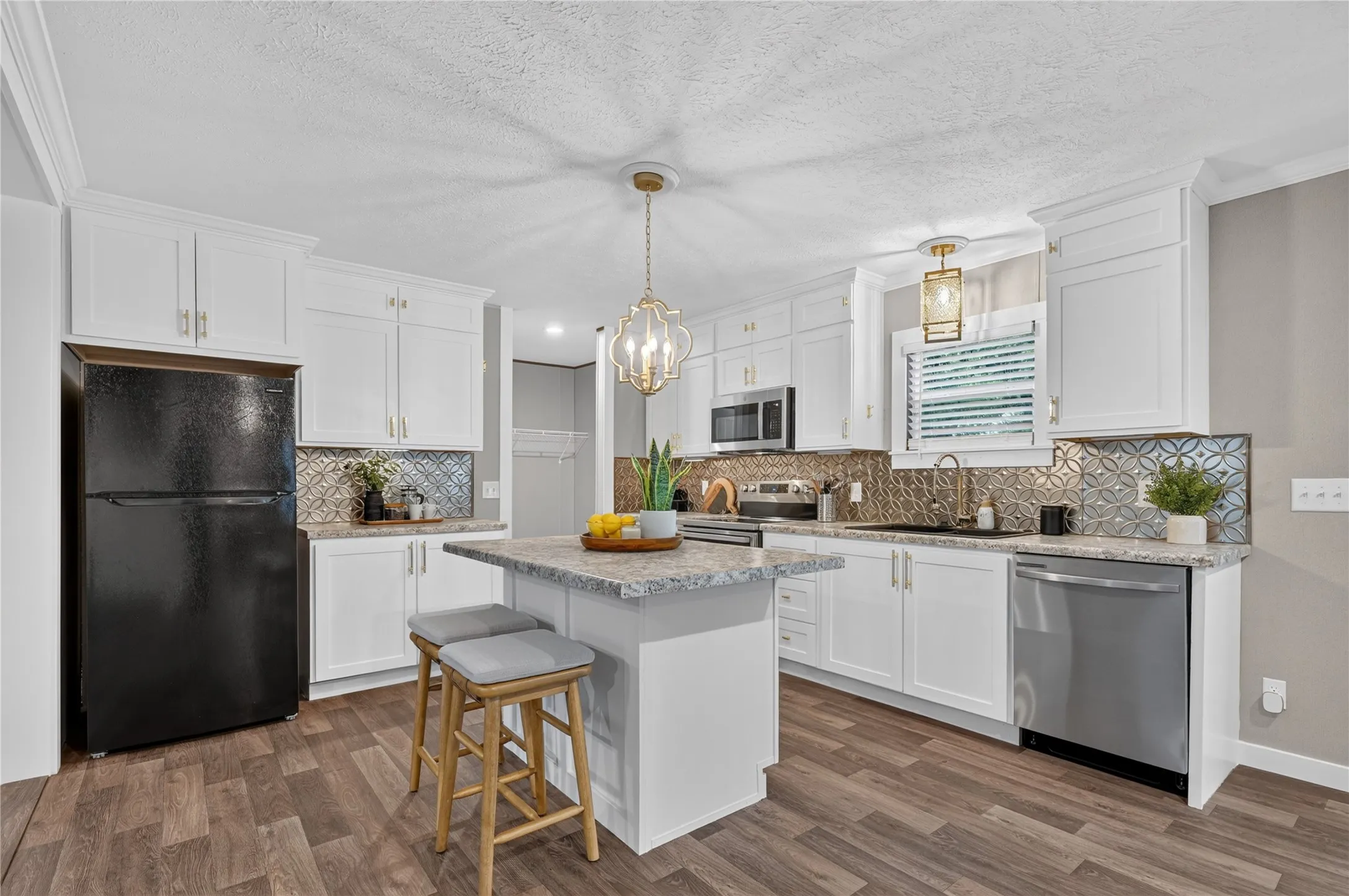 Kitchen featuring white cabinetry, patterned backsplash, wood-finish flooring, and a center island with a stone-finish countertop