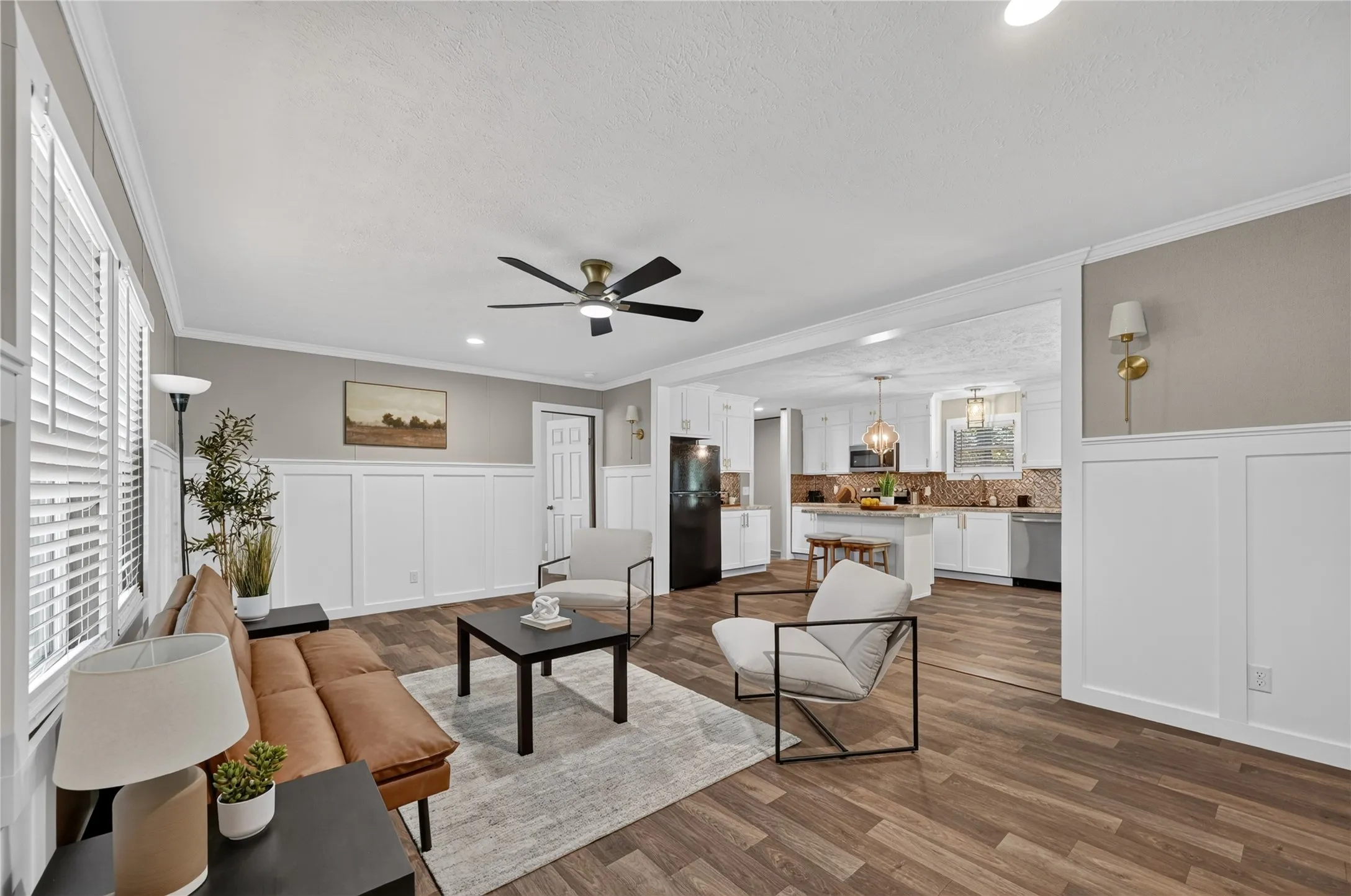 Spacious room featuring wood-finish flooring, white wainscoting, and a ceiling fan