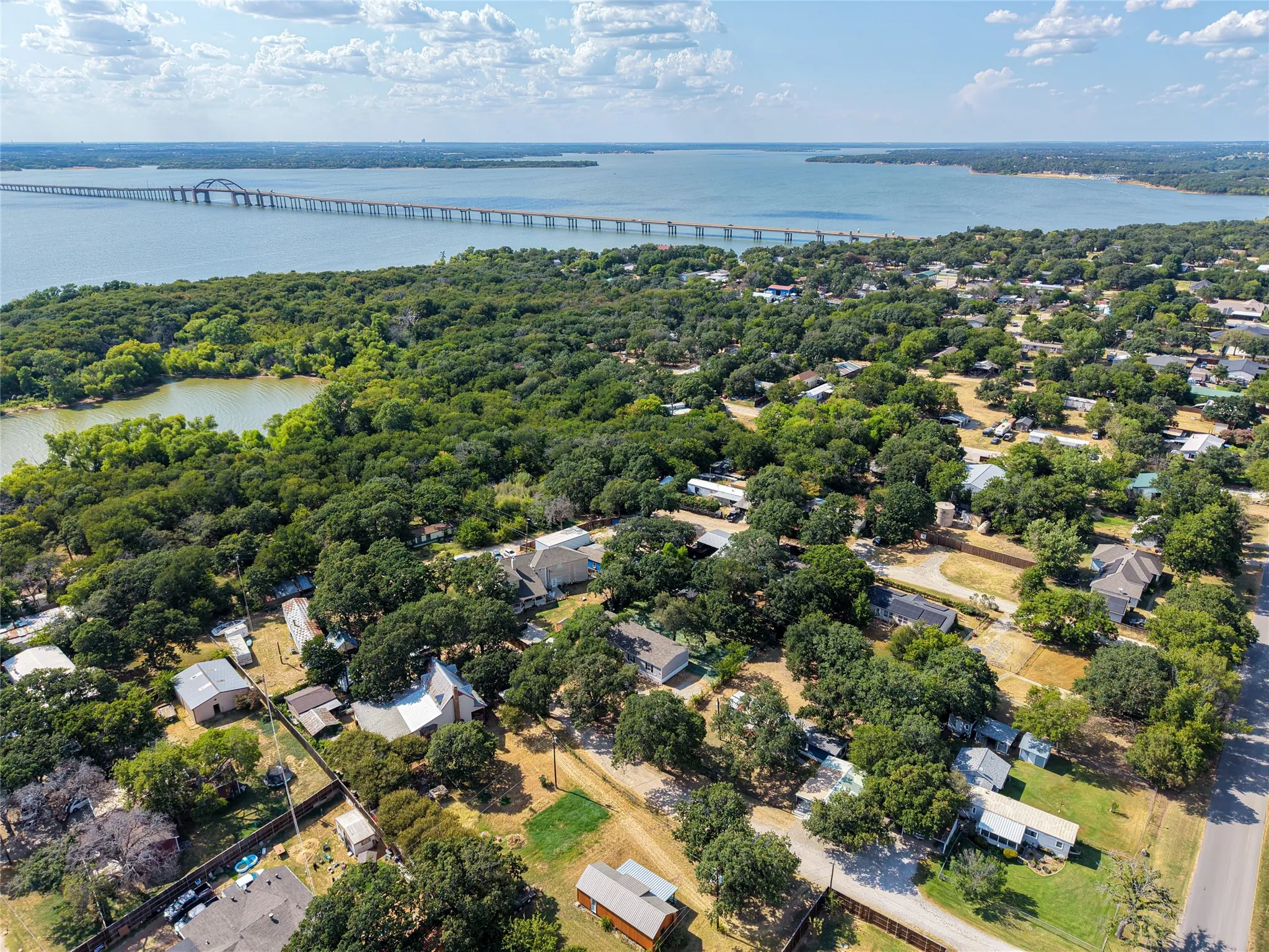 Expansive water body with a prominent bridge structure, surrounded by a densely treed landscape