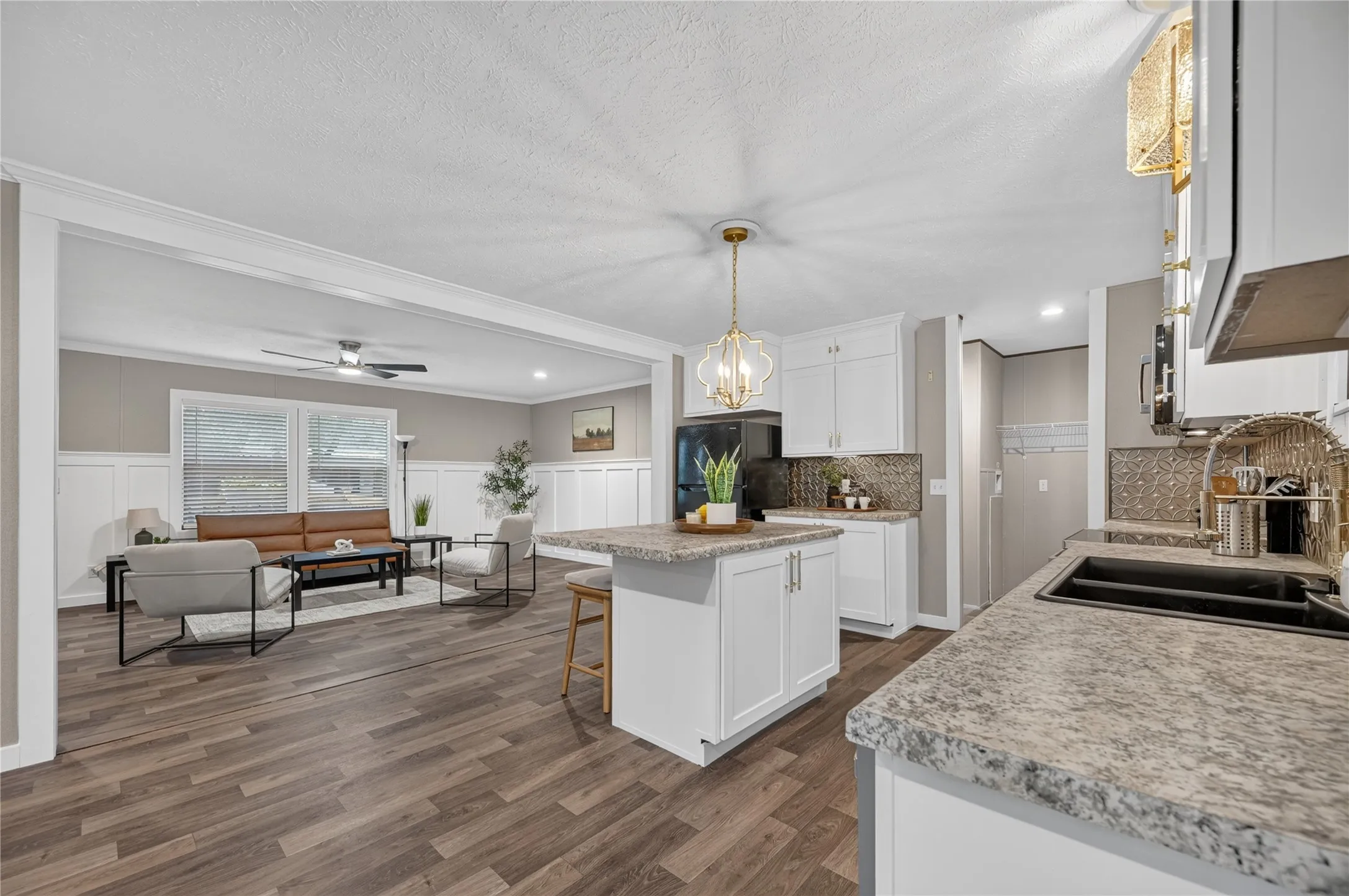 Open-concept layout with wood-finish flooring, white cabinetry, and granite-style countertops