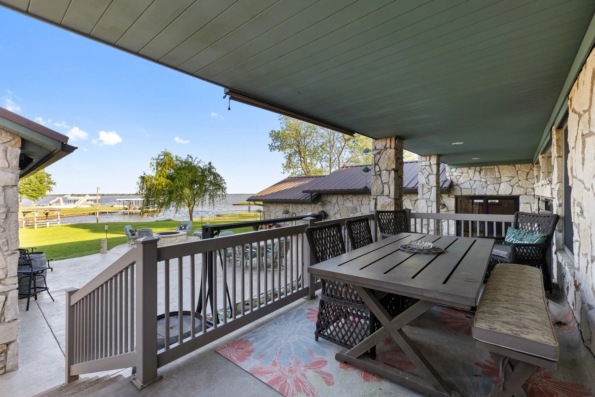 Covered patio with stone columns and walls, overlooking a waterfront expanse
