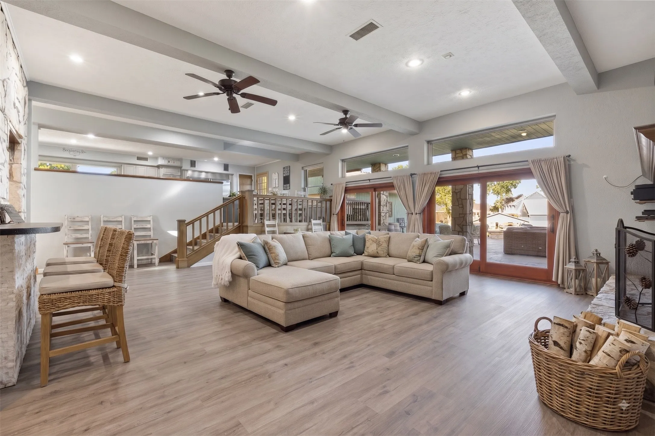 Spacious open-concept living area featuring wood-finish flooring, exposed ceiling beams, and recessed lighting