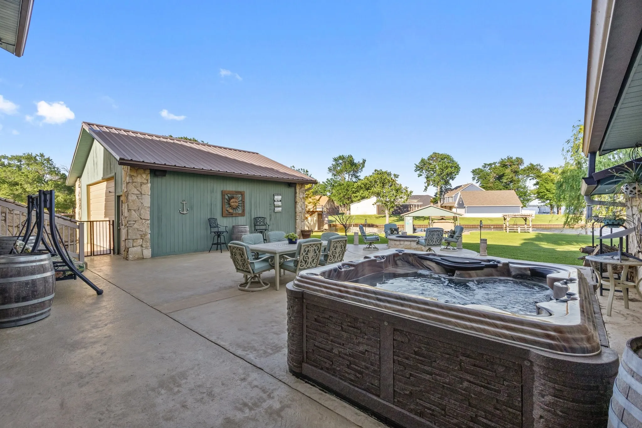 Expansive patio featuring a built-in hot tub, concrete surfacing, and a dedicated outdoor dining area