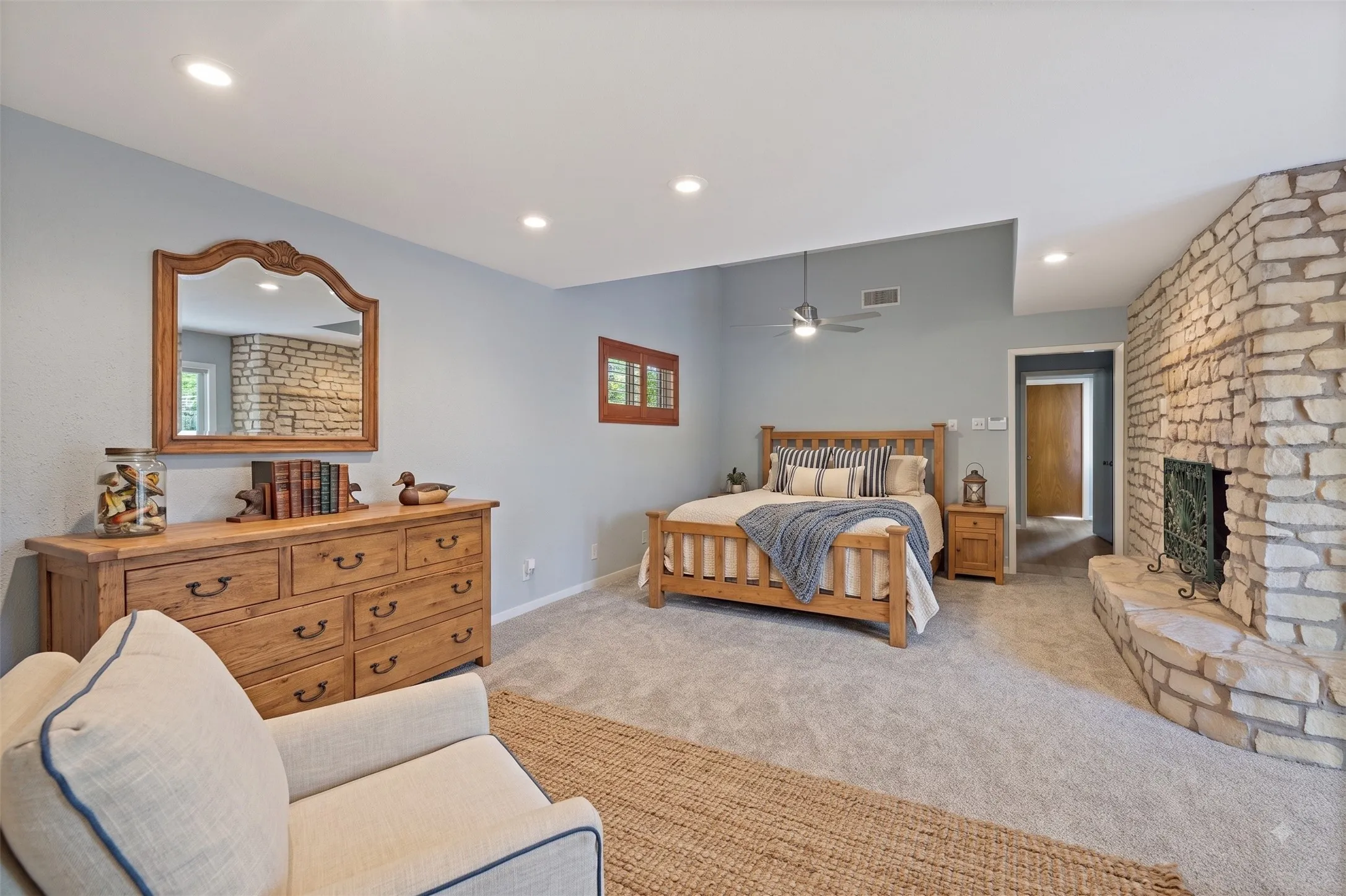 Stone-clad fireplace with hearth, recessed lighting, vaulted ceiling, and ceiling fan