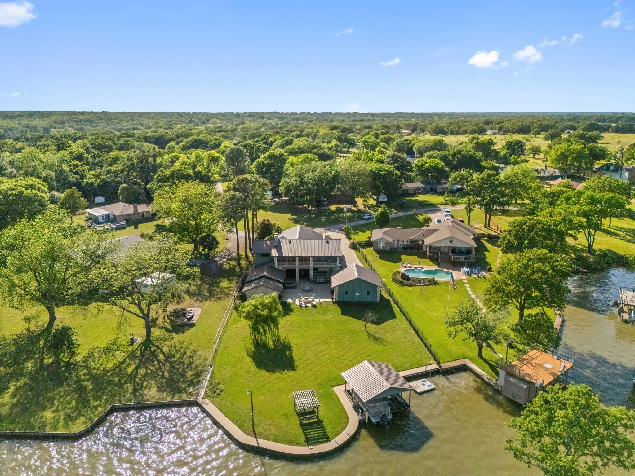 Expansive waterfront property featuring a boat dock, boat lift, private swimming pool, and multiple outdoor living areas