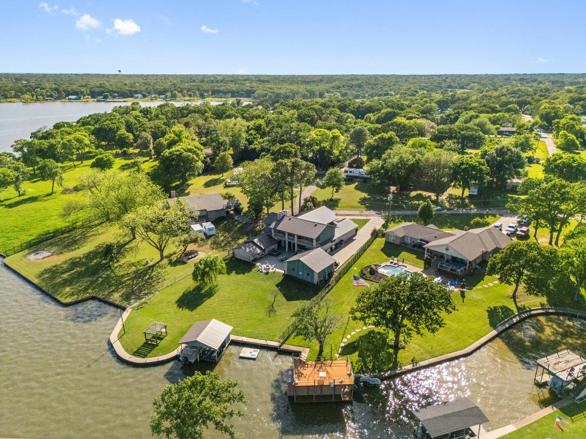 Waterfront property featuring multiple structures, a swimming pool, private boat docks, and a lush green lawn