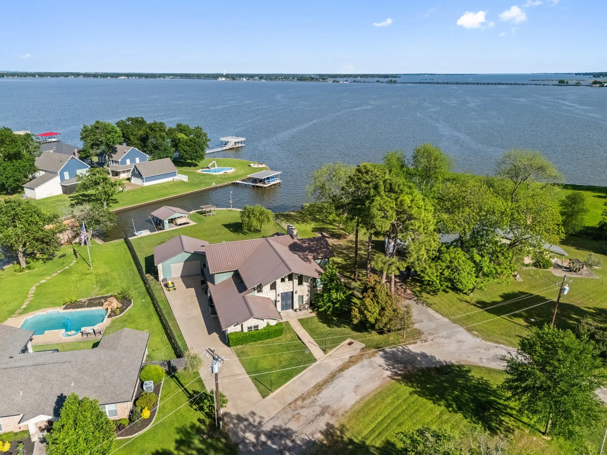 Spacious property with a large body of water, private boat dock, well-maintained lawn, and mature trees