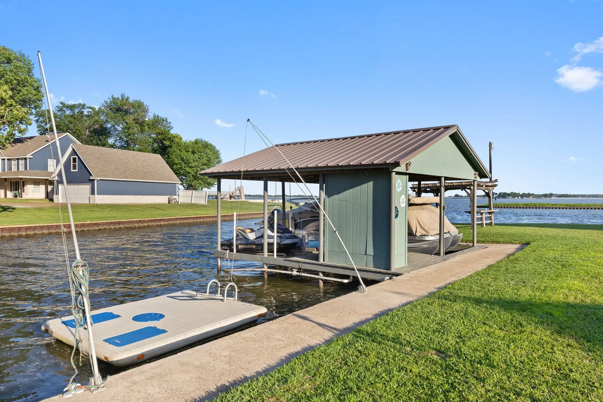 Waterfront property featuring a private boat dock with covered slip, composite decking, and integrated mooring infrastructure