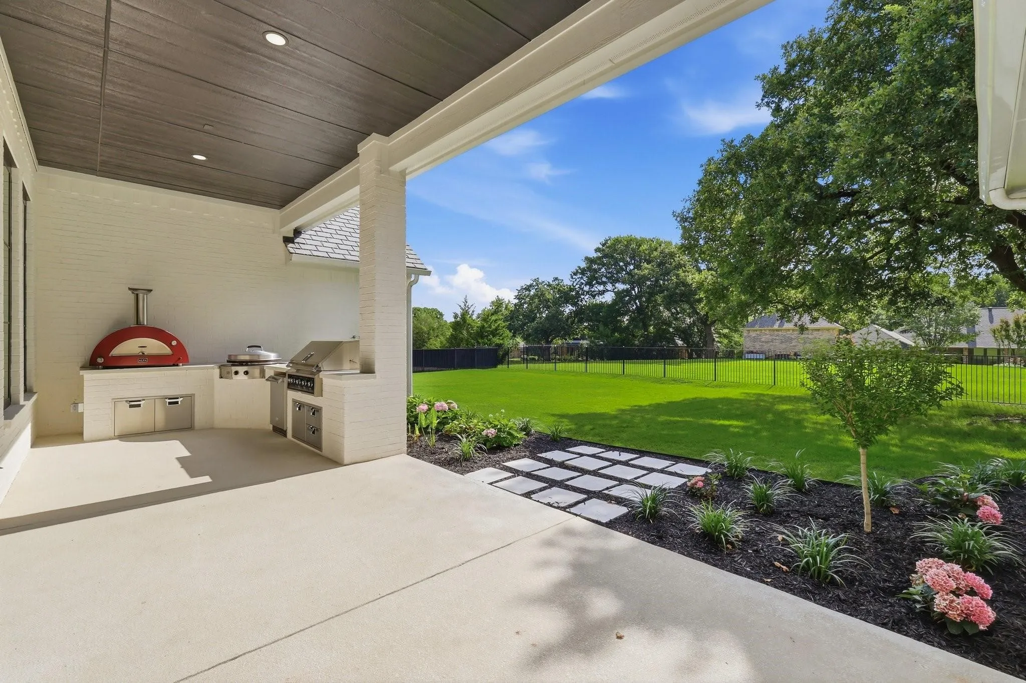 Fully equipped outdoor kitchen features a Hestan outdoor refrigerator, a Hestan Aspire 42in built-in gas grill, an EVO 30G built-in flat-top, and an authentic Alfa Moderno 3 Italian gas pizza oven with a dedicated prep area.