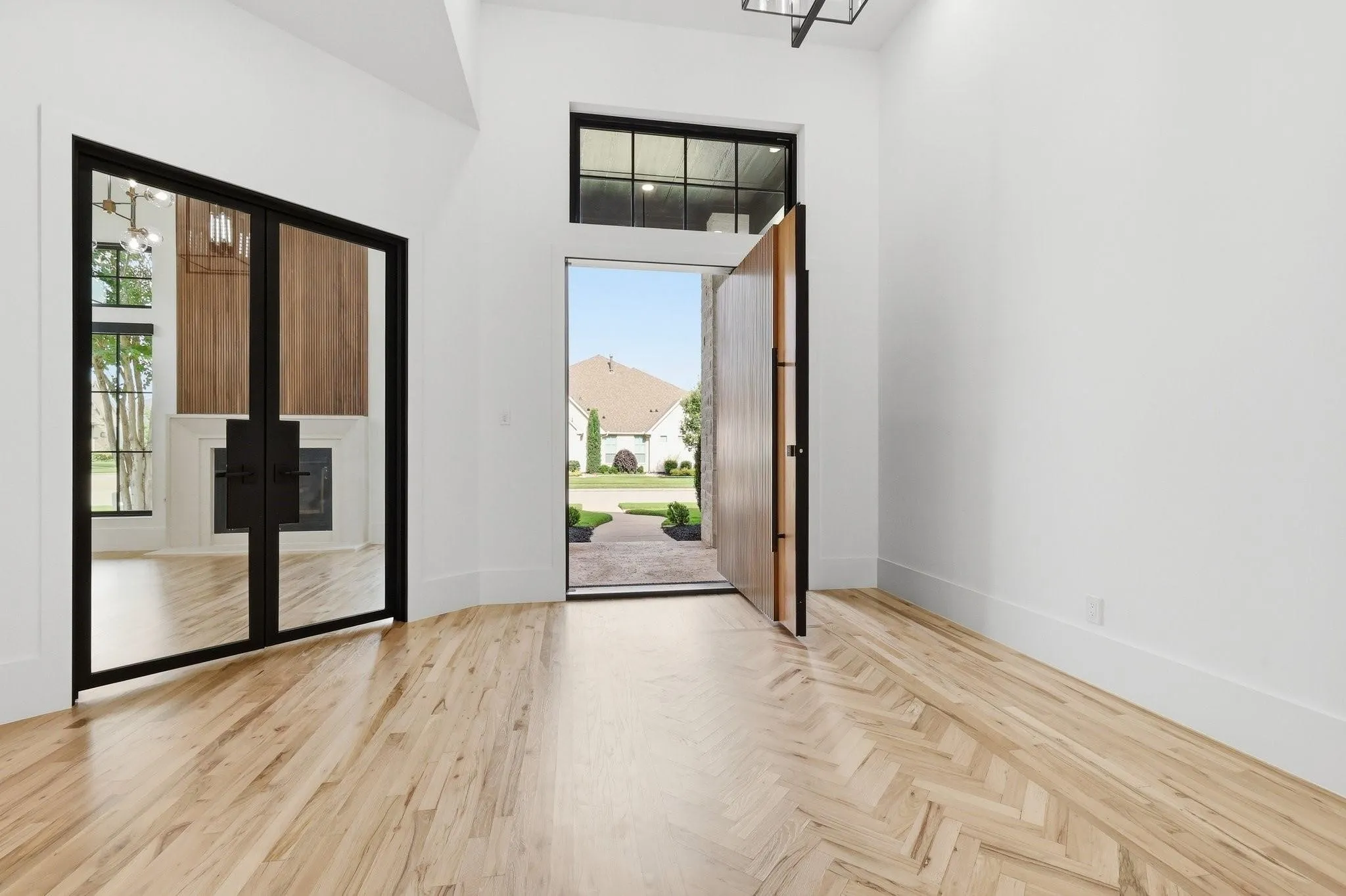 Spacious entry way with pivot front door and view of office with French iron doors