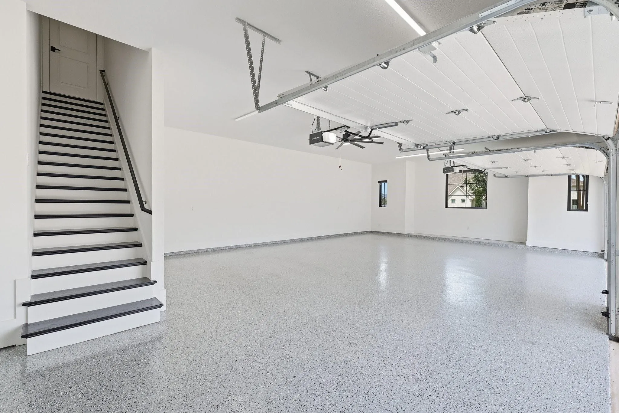 4 car garage with an epoxy finish, a finished staircase leading to upper level floored attic storage.